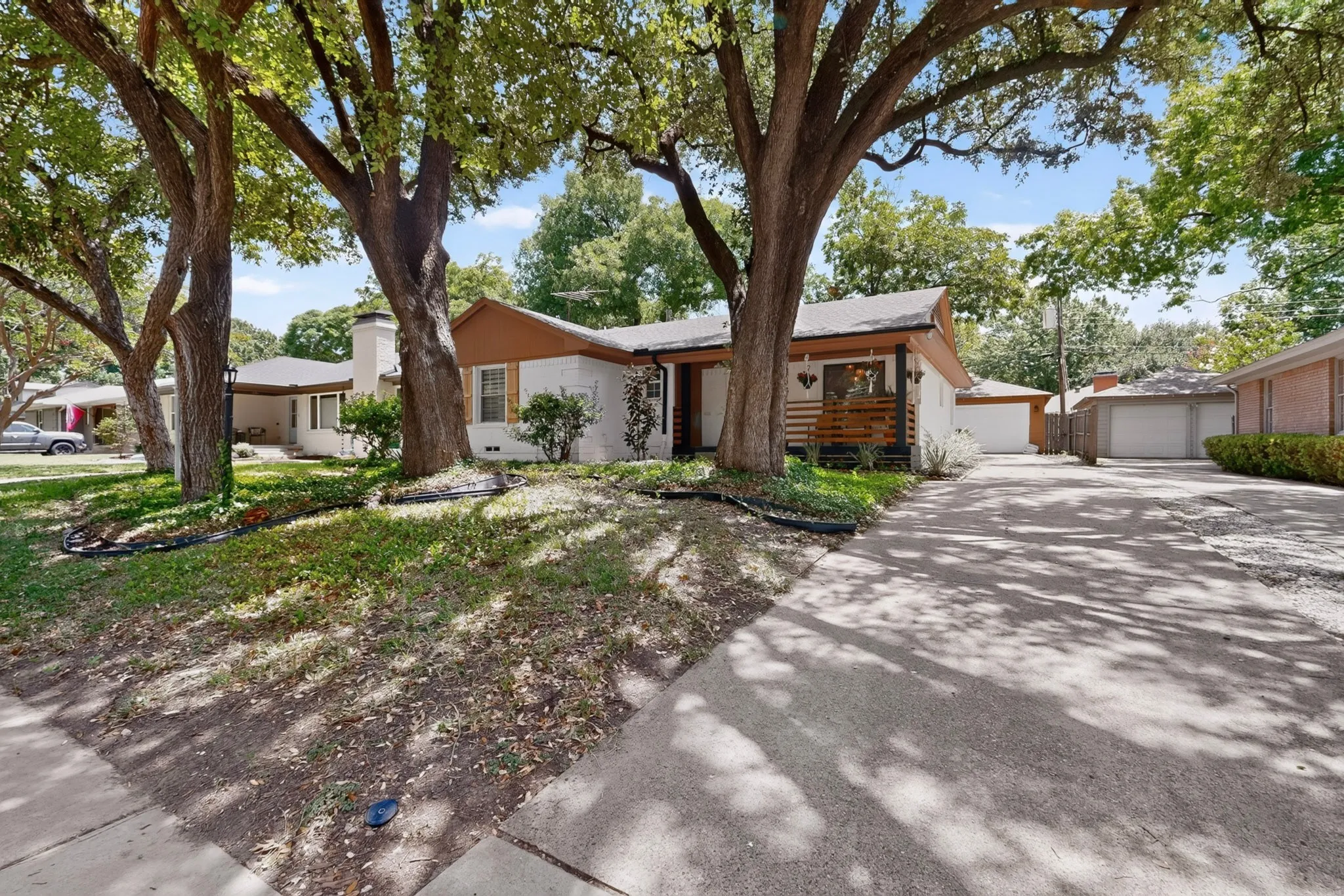 Ranch-style residence featuring a white brick exterior, brown trim, and a concrete driveway