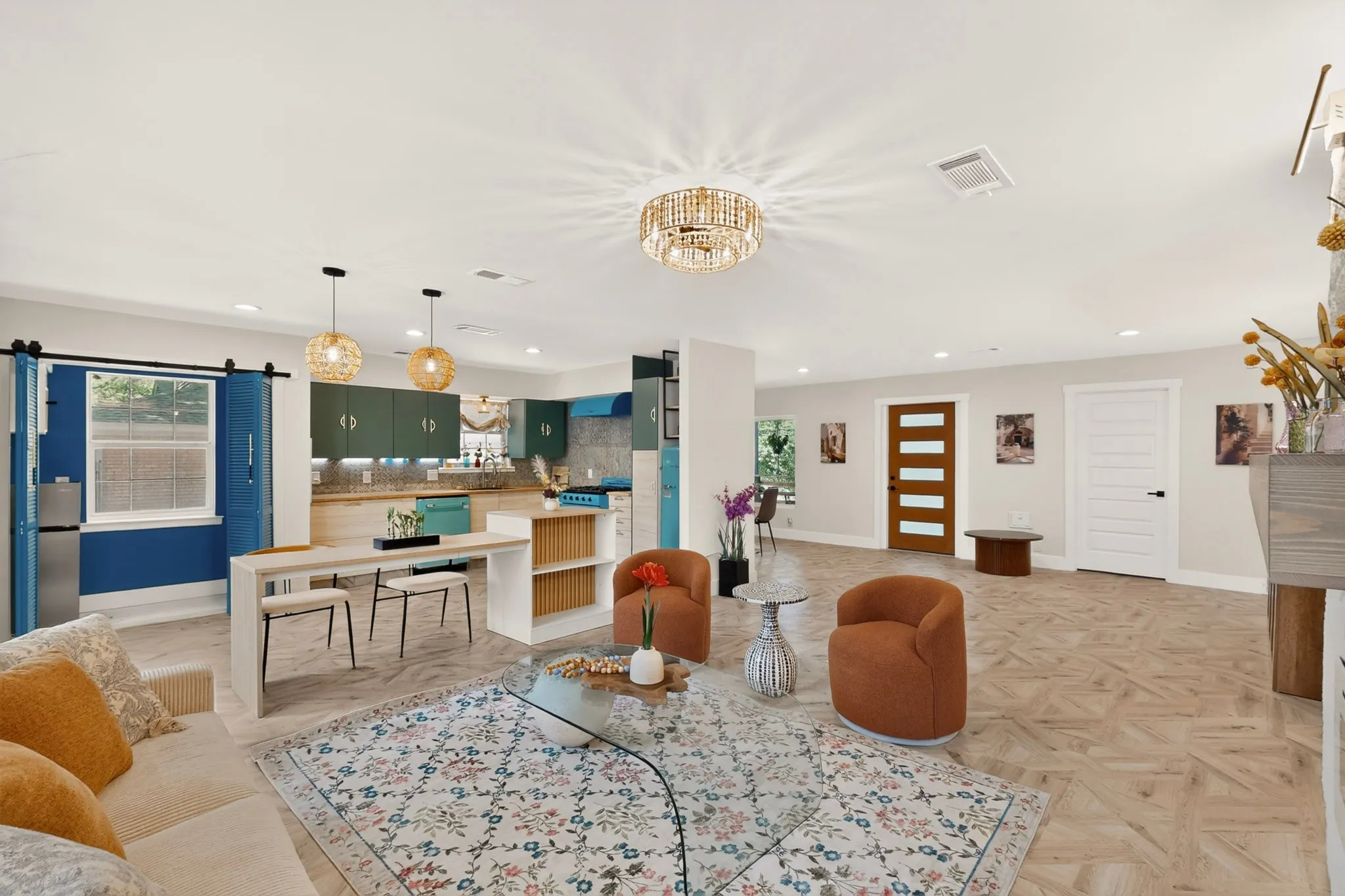 Open-concept living area featuring light wood-finish flooring, a contemporary gold chandelier, recessed lighting, and a kitchen with dark green cabinetry and light wood countertops