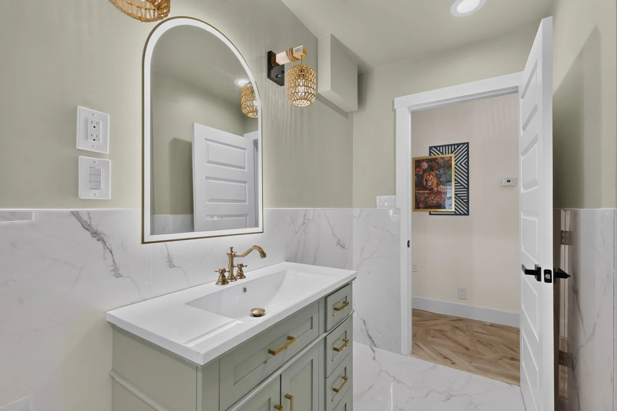 Bathroom featuring a light green vanity with brass hardware, a white countertop, and a white rectangular undermount sink with a brass faucet