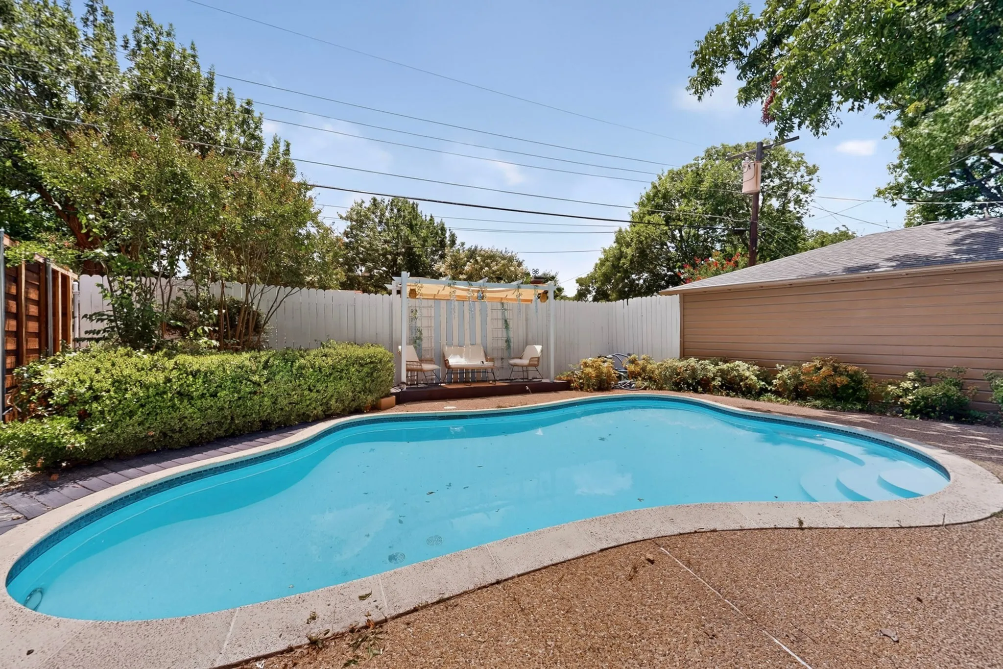 Kidney-shaped swimming pool featuring concrete decking and integrated steps