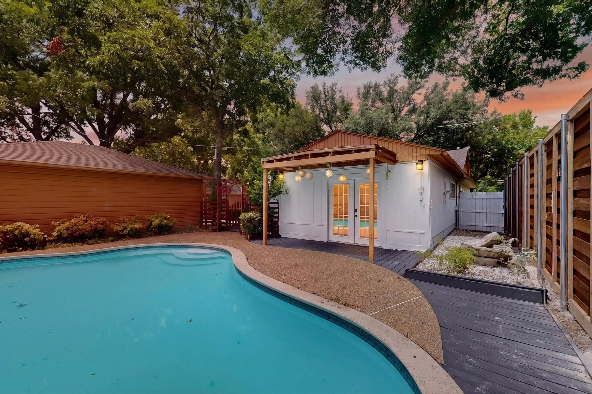 Curved swimming pool featuring integrated steps and a surrounding aggregate deck
