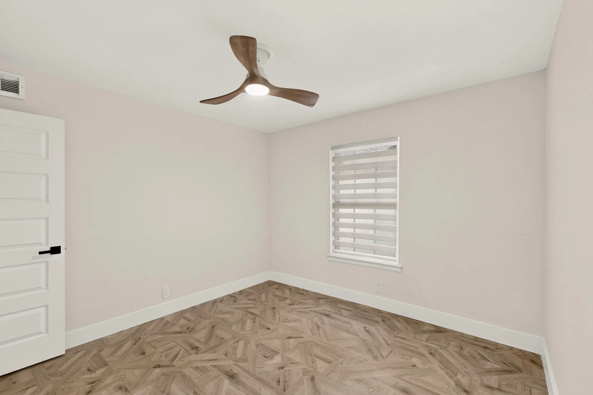 Room featuring wood-finish flooring with a geometric pattern, neutral wall paint, and white baseboards