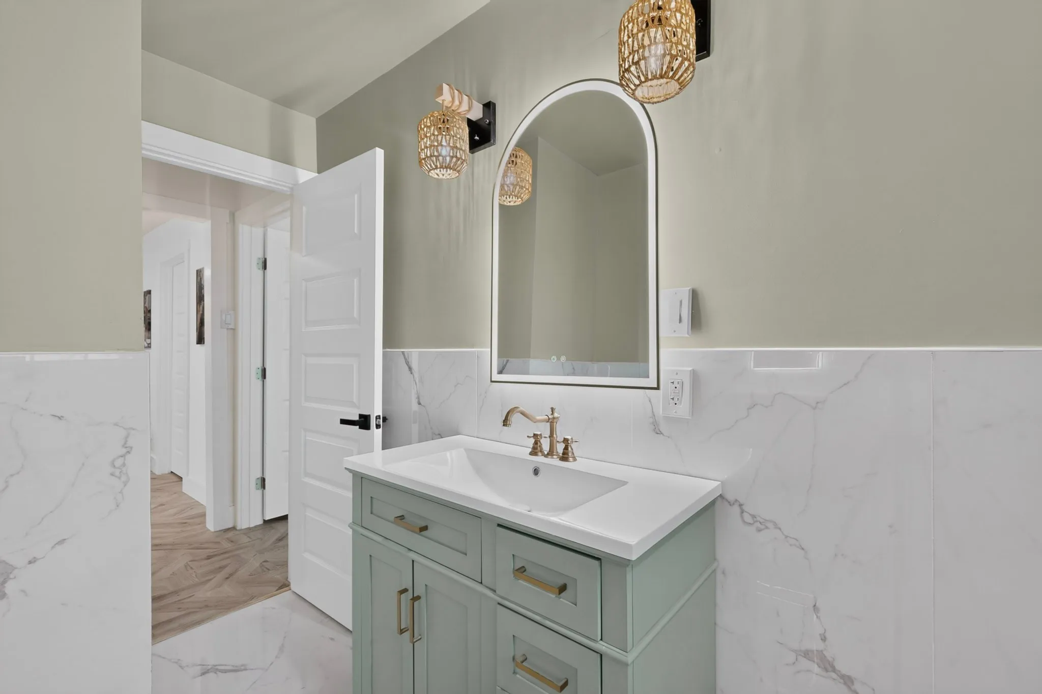 Bathroom featuring a light green vanity with brass hardware, a white countertop, and an undermount sink