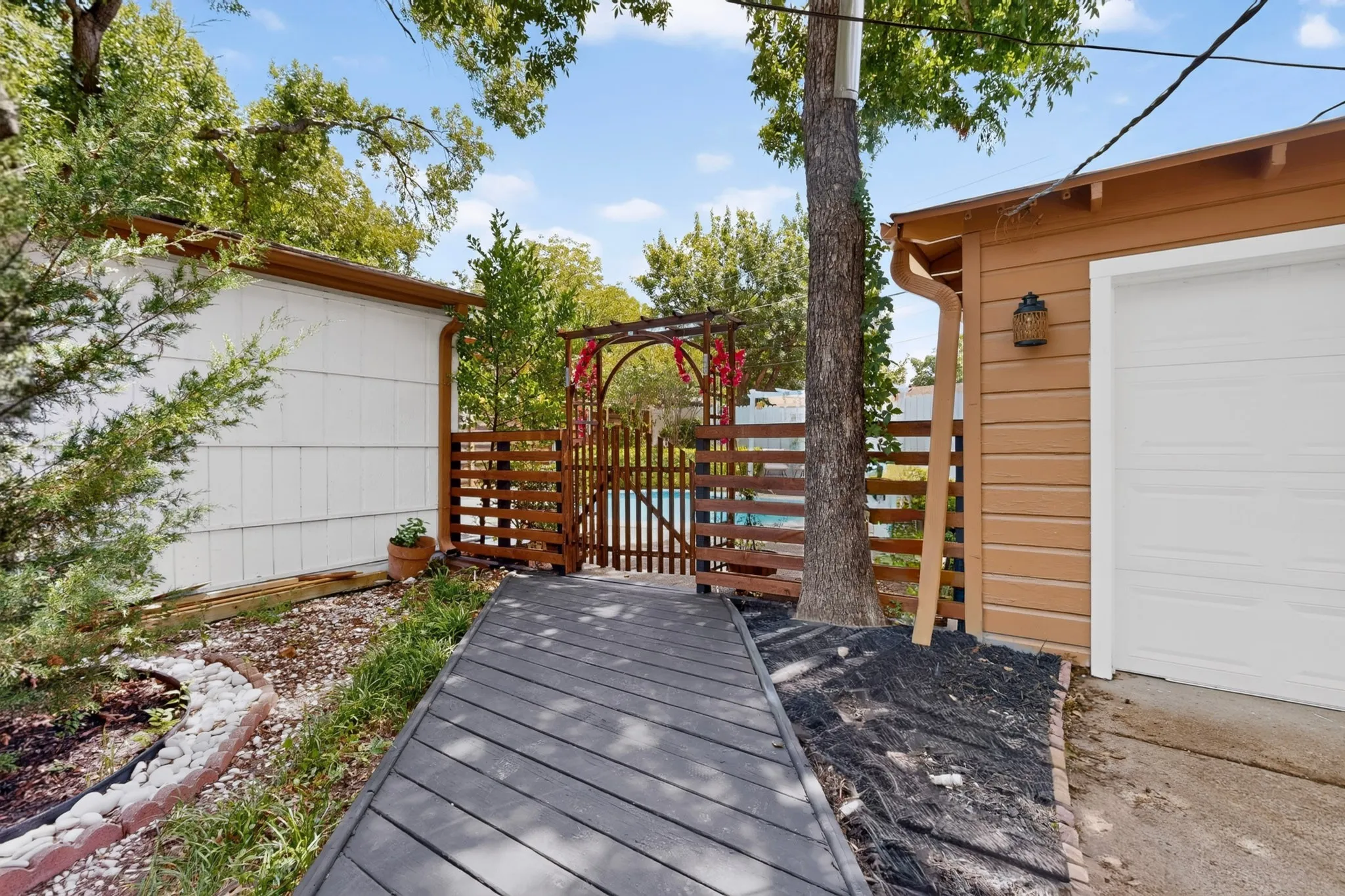 Deck walkway with composite decking, leading to a wooden gate and fenced area