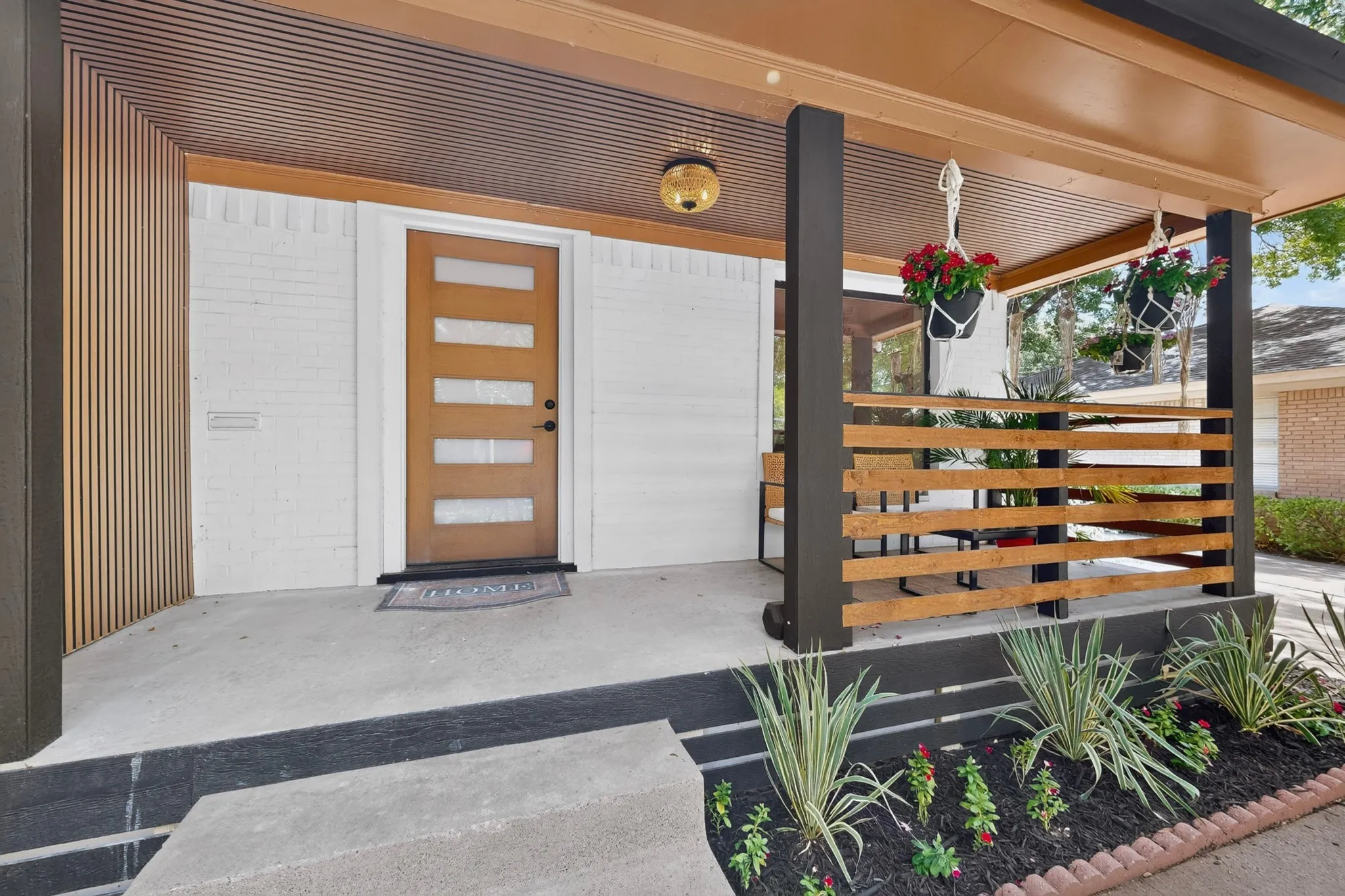 Entryway featuring a modern wood-paneled door with frosted glass inserts, white brick facade, recessed lighting, wood-finish porch ceiling, and a slatted wood railing