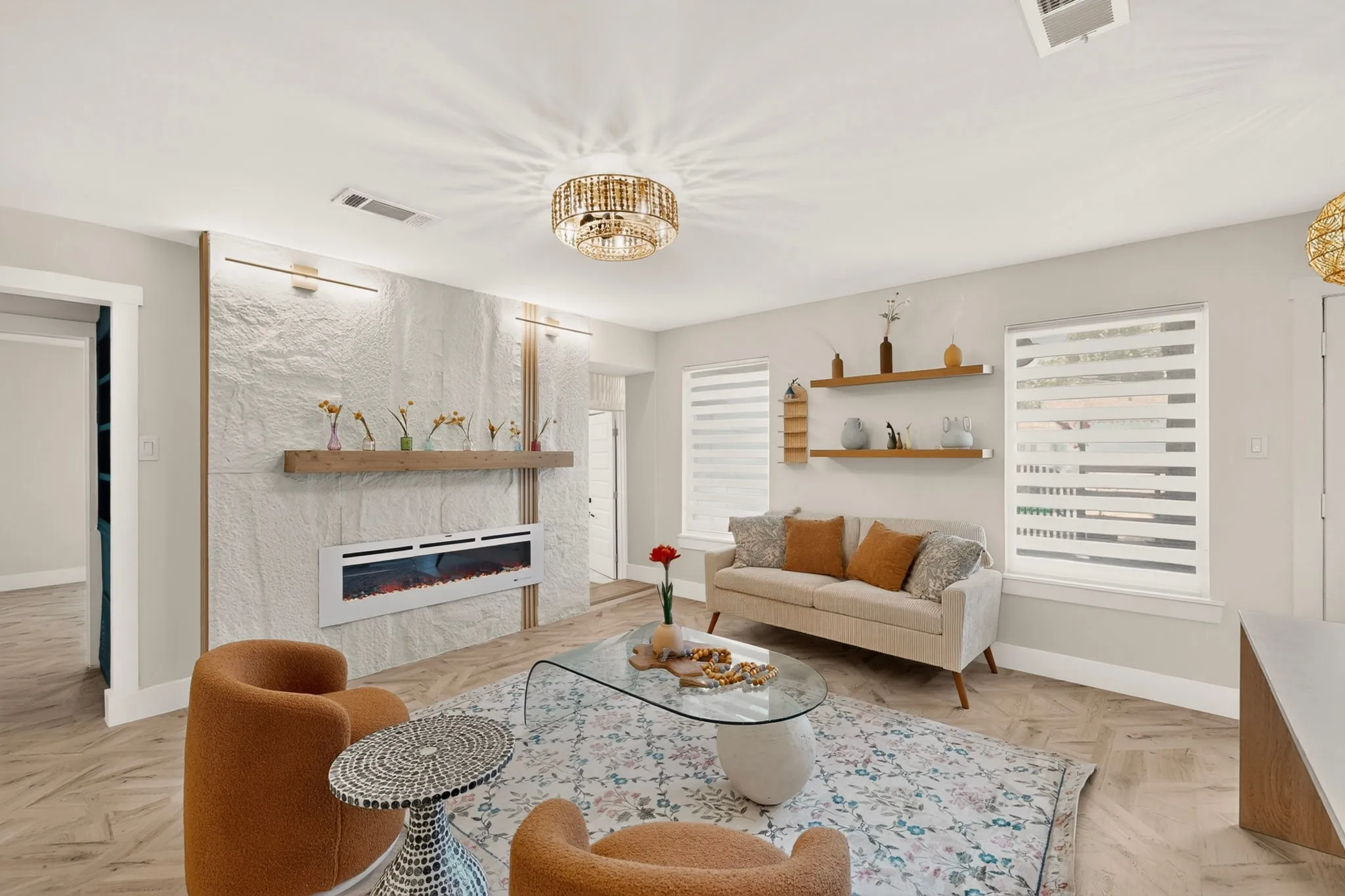Living space featuring a textured accent wall, integrated electric fireplace, and a wood-finish mantel