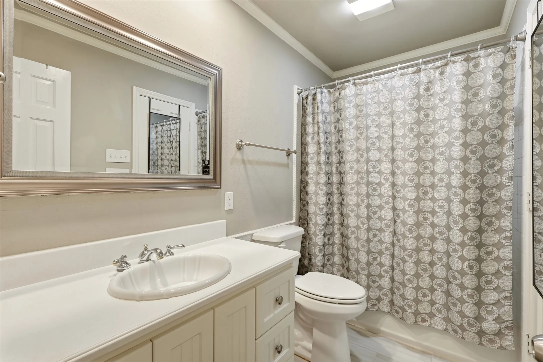 Vanity featuring a dark granite countertop with an undermount sink, white cabinetry with silver hardware, and a framed mirror
