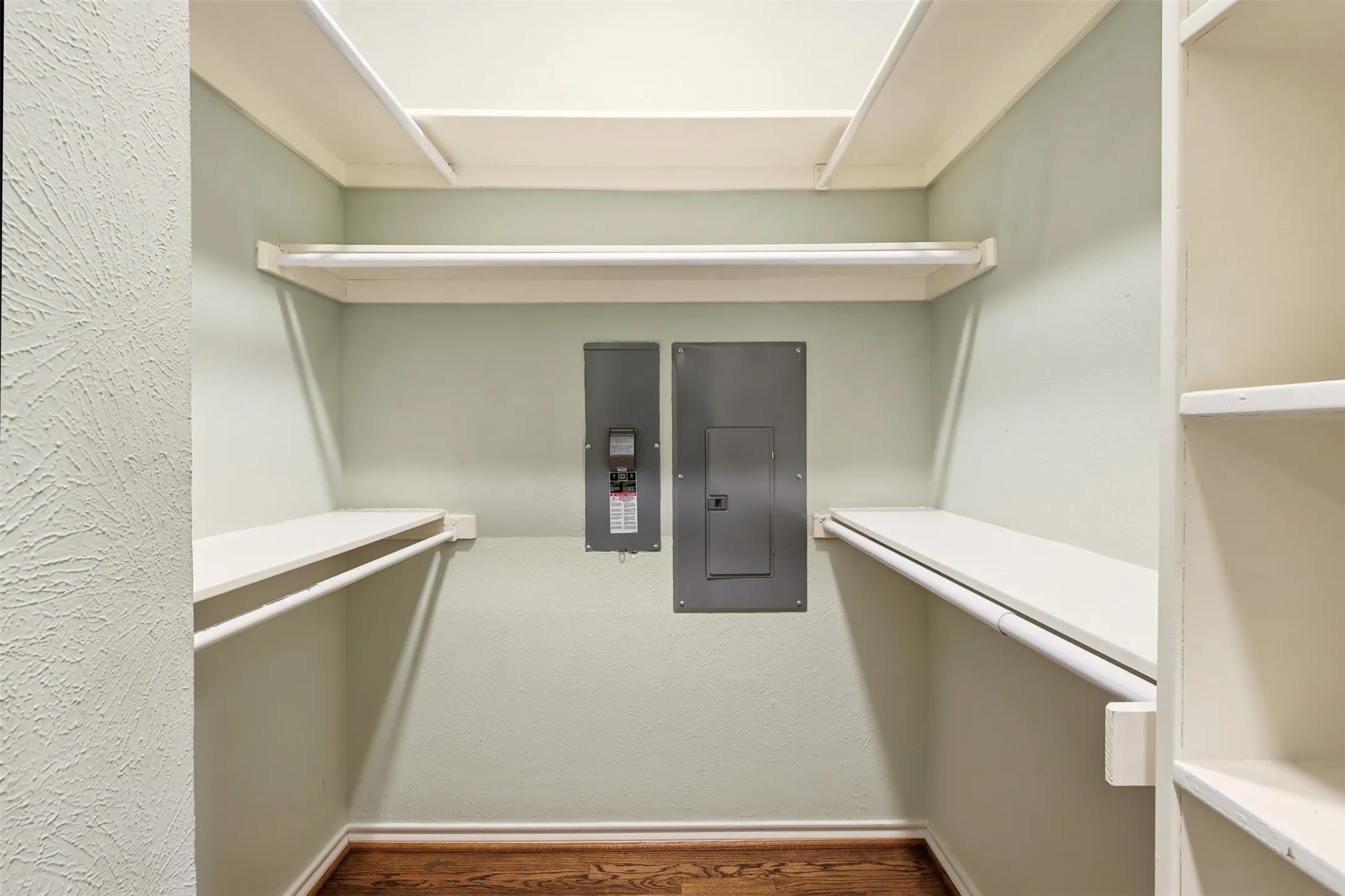 Closet featuring built-in shelving, hanging rods, hard surface flooring, and light-toned wall paint