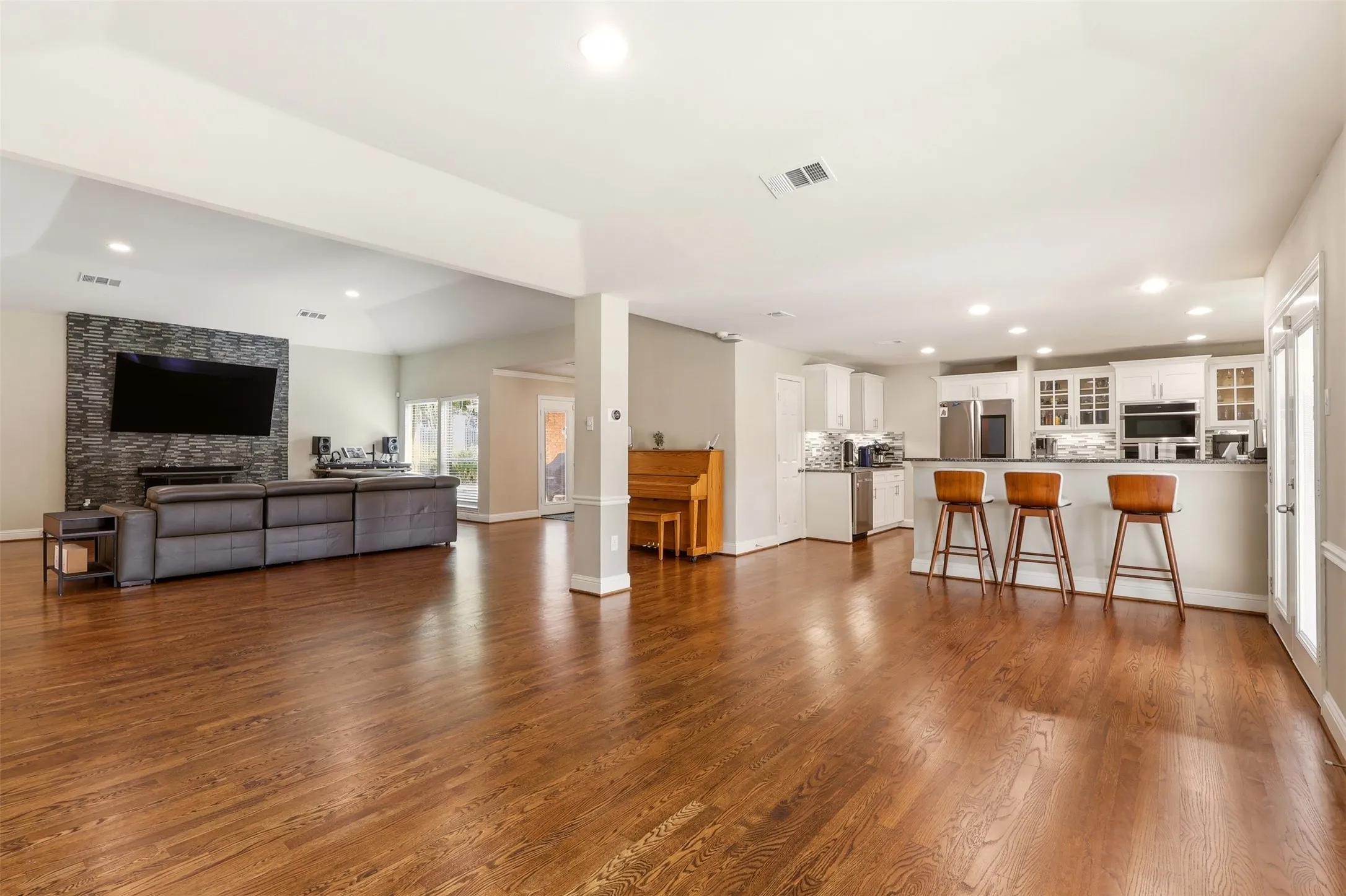 Spacious kitchen featuring white cabinetry, stainless steel double wall ovens, granite countertops, a decorative tile backsplash, and wood-finish flooring