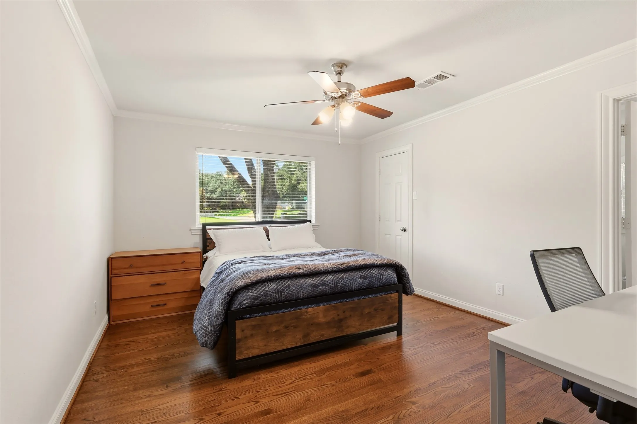 Bedroom featuring wood-finish flooring, a ceiling fan with light fixture, white walls, and crown molding