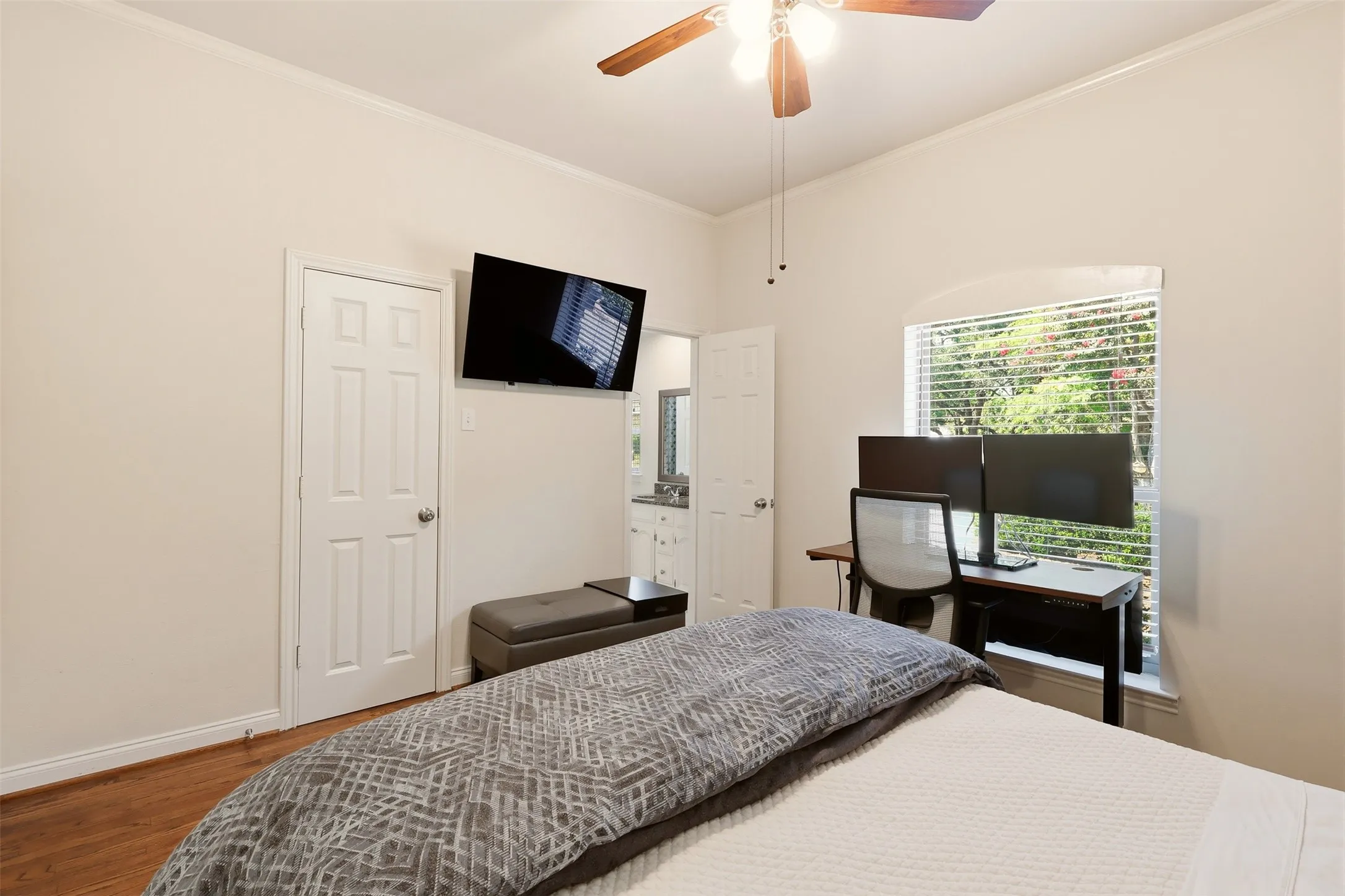 Bedroom featuring wood-finish flooring, a ceiling fan with integrated lighting, and a window with blinds
