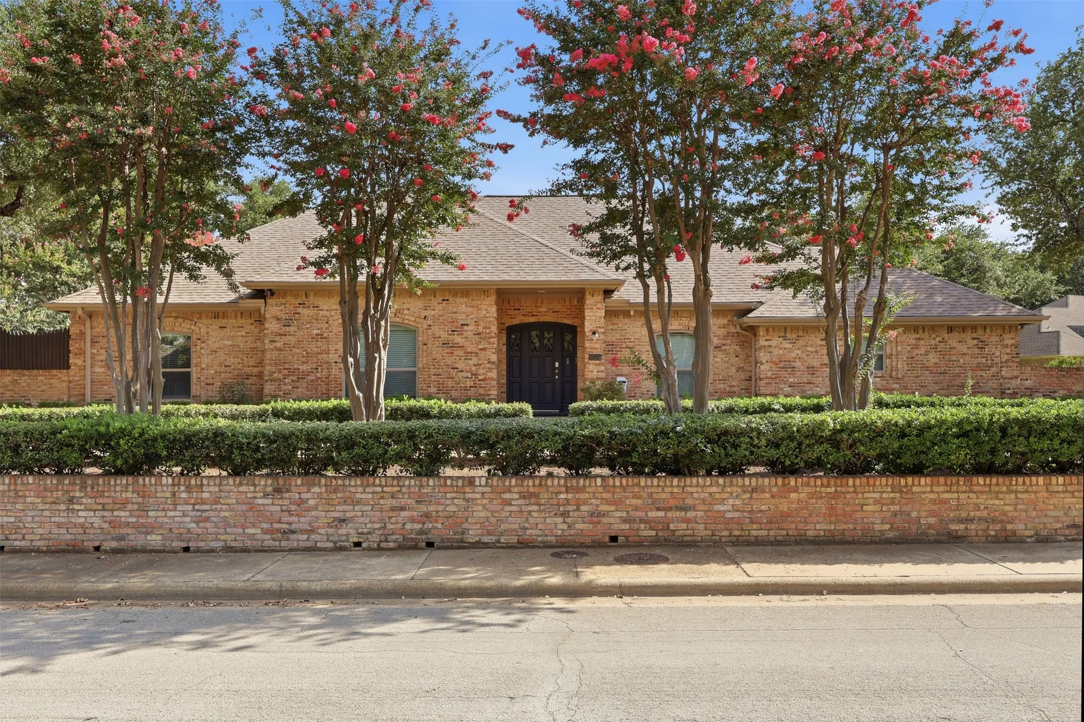 Brick facade residence featuring a dark arched entry door