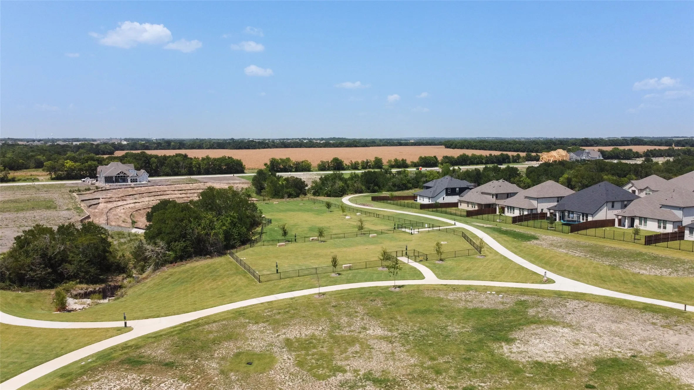 Expansive green spaces featuring walking paths and fenced amenity areas