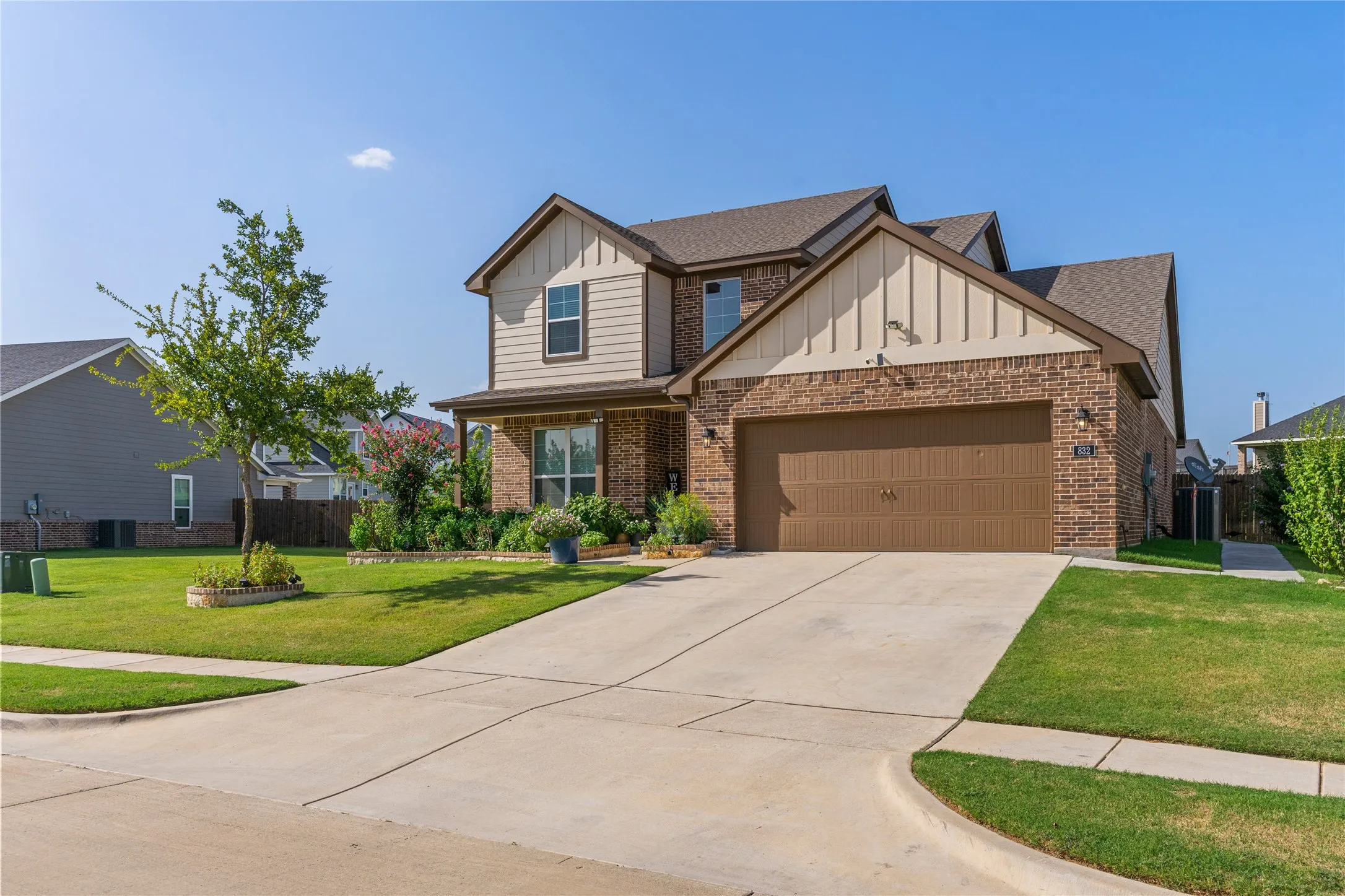 Two-story residence featuring a brick and siding exterior, an attached two-car garage, and a concrete driveway