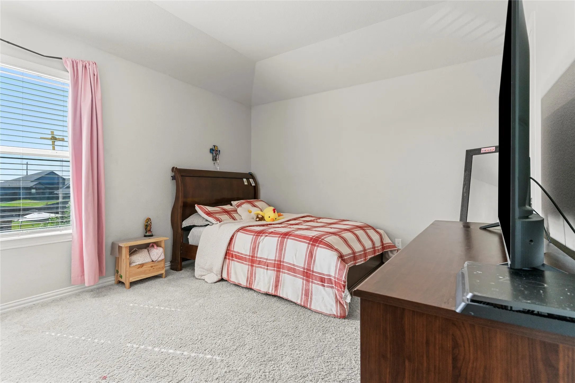 Light-filled room featuring a large window with blinds, a tray ceiling, light gray carpeting, and a dark wood-finish dresser