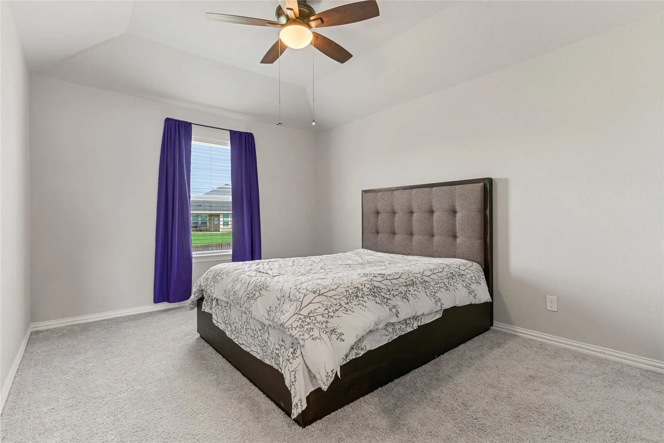 Spacious room with a vaulted ceiling and a ceiling fan