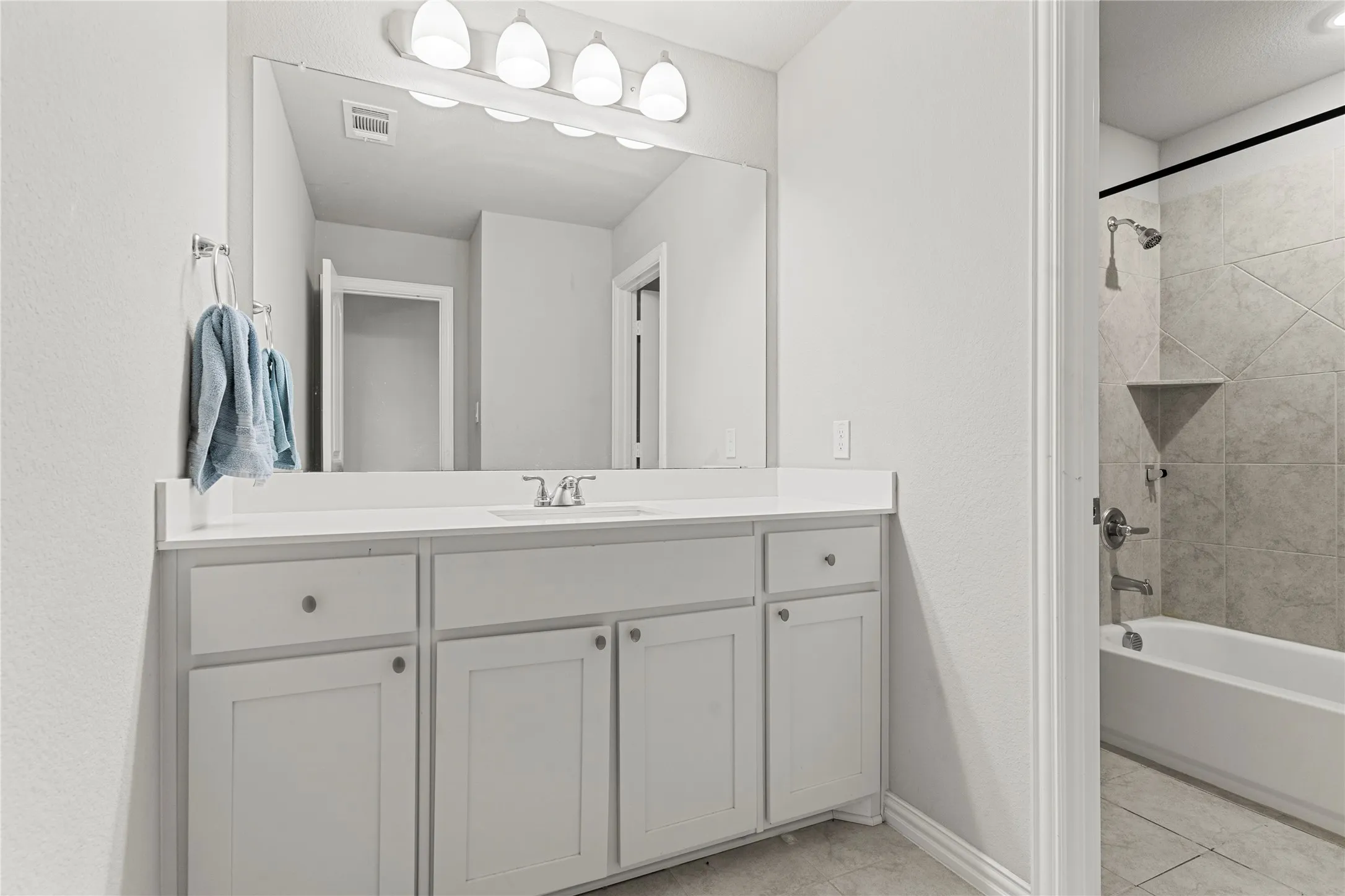 Bathroom vanity featuring white shaker cabinetry with brushed nickel hardware, a white countertop, and a large rectangular mirror