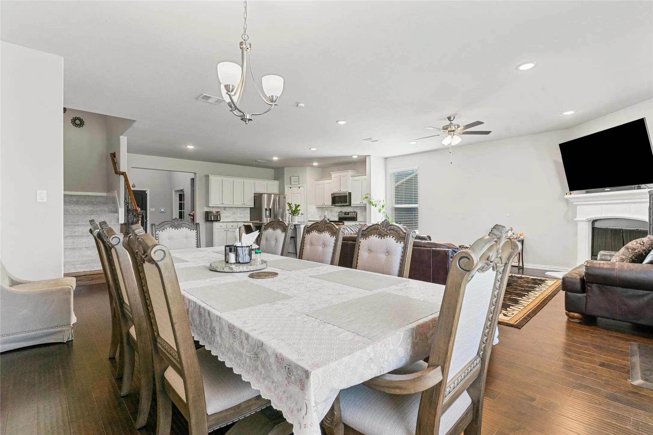 Open-concept living area featuring dark wood-finish flooring, recessed lighting, and a white fireplace mantel