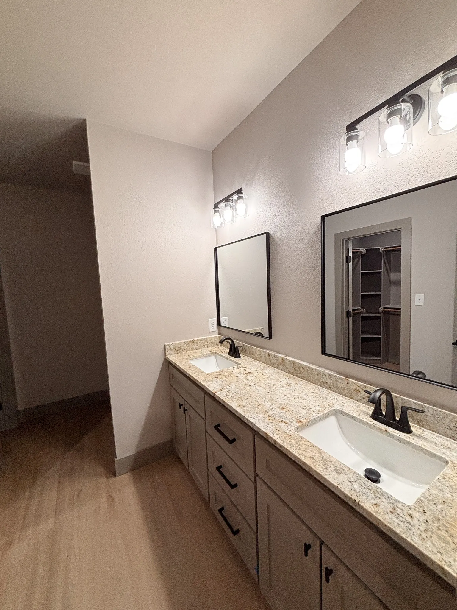 Dual vanity featuring light-toned cabinetry with black hardware, granite-style countertops, and undermount sinks