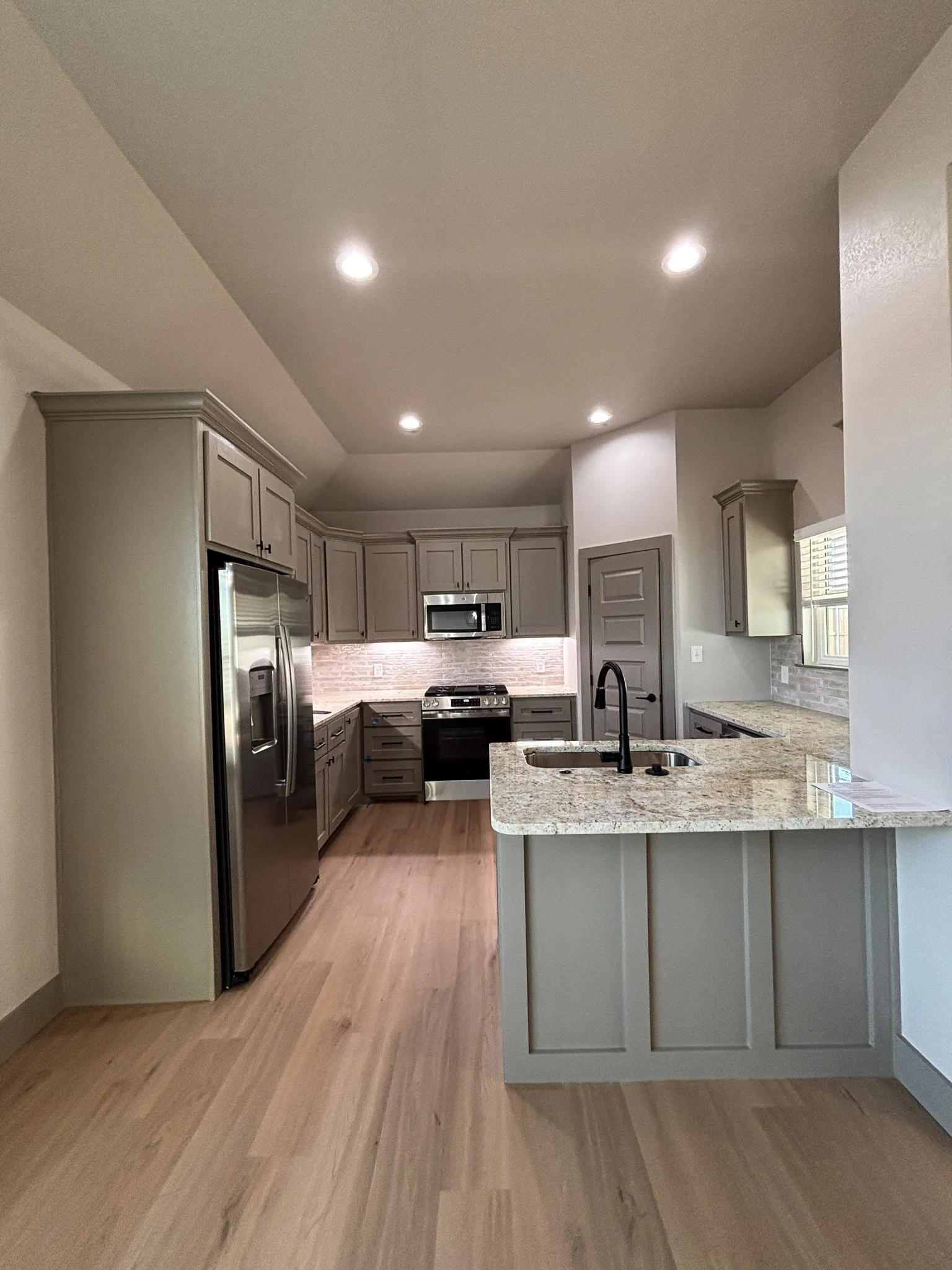 Modern kitchen featuring light wood-finish flooring, recessed lighting, and a neutral color palette