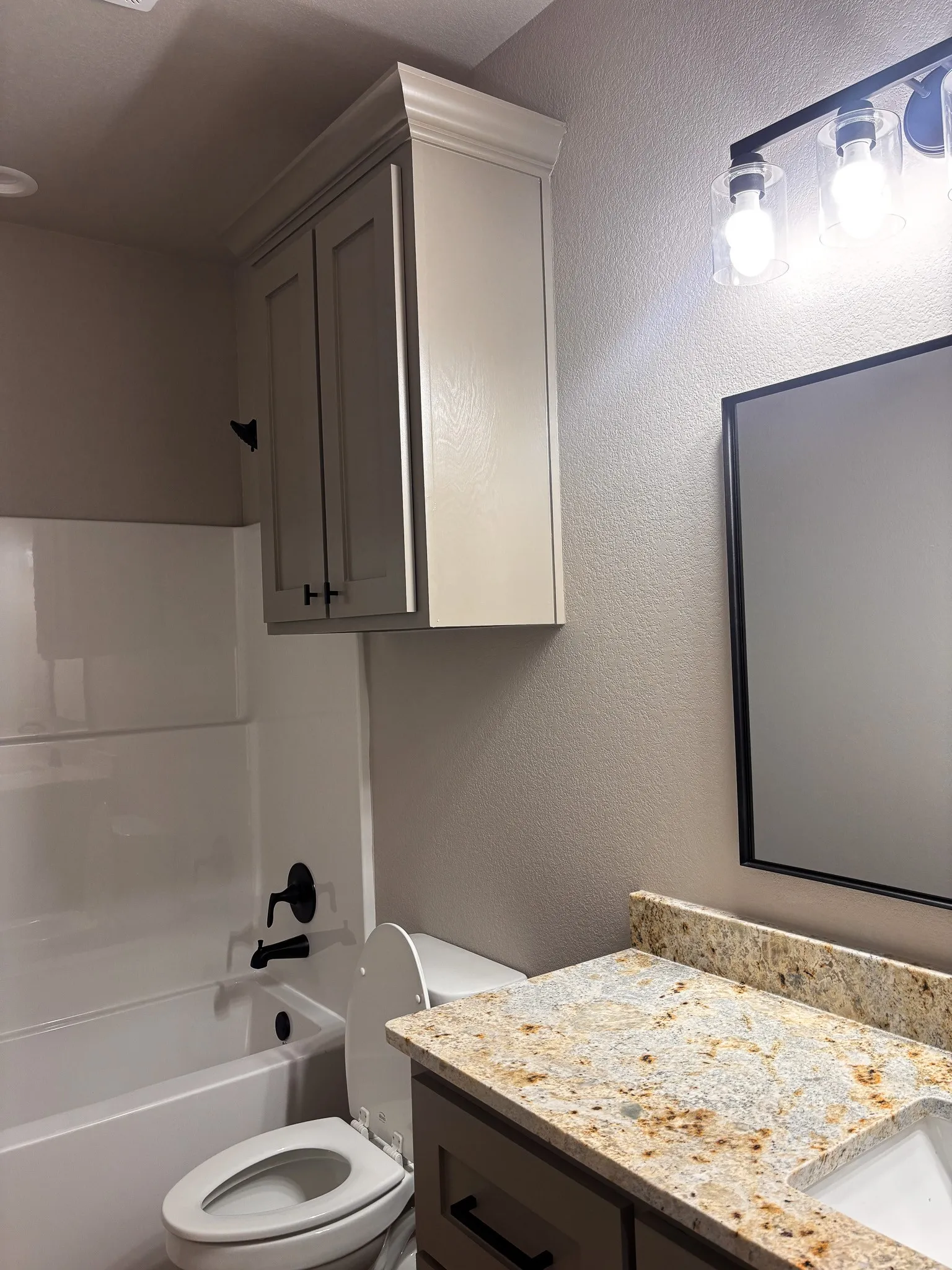 Bathroom vanity featuring a speckled countertop and an undermount sink