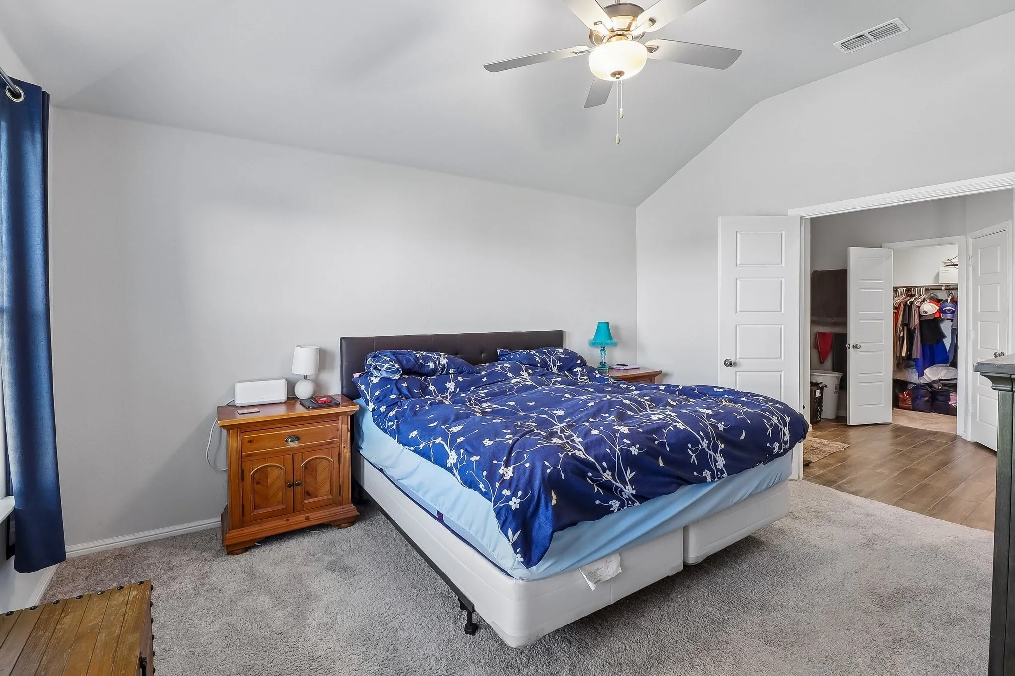 Vaulted ceiling bedroom featuring plush gray carpet and a ceiling fan with integrated lighting