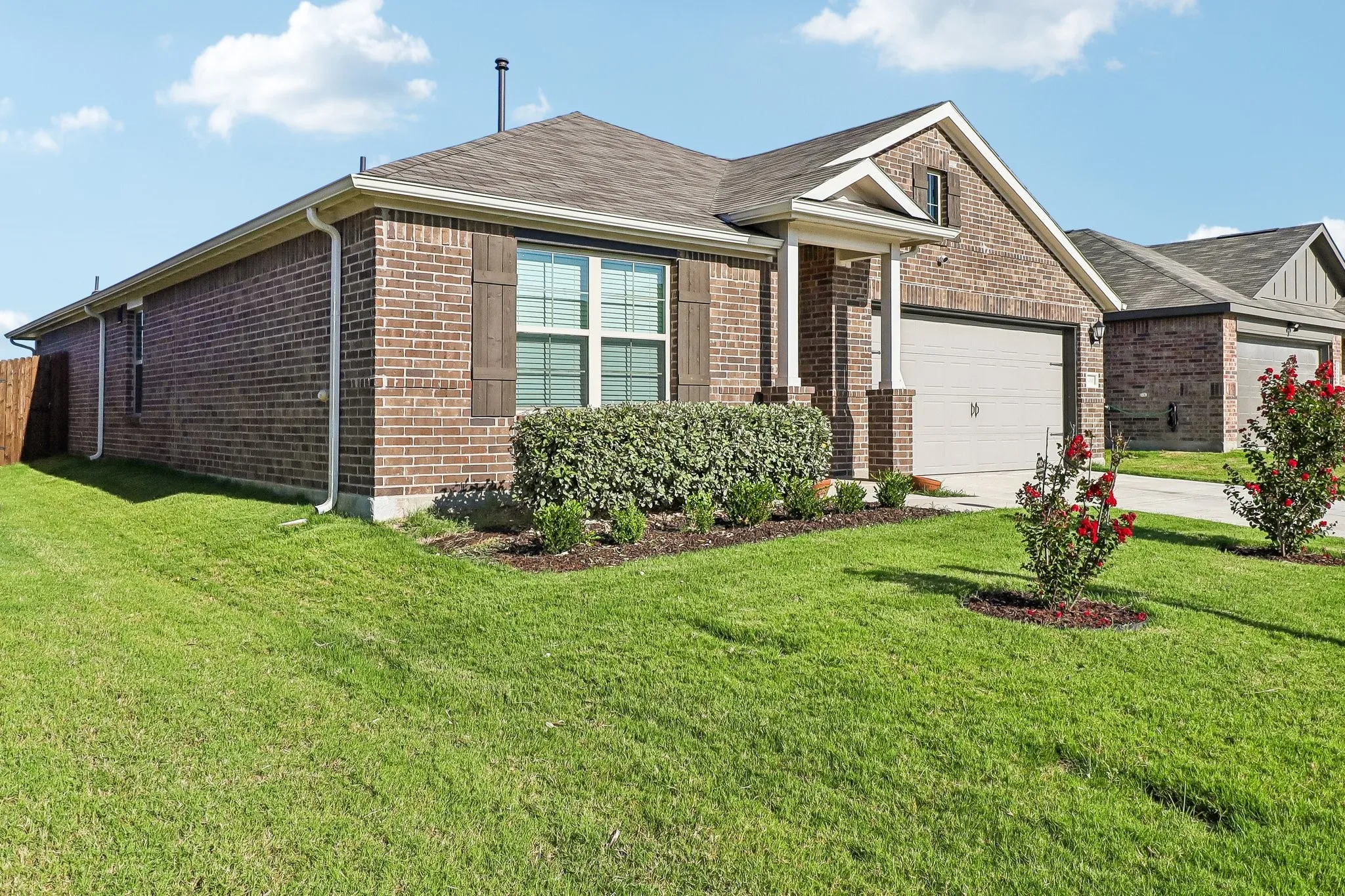 Brick exterior with a gabled roofline, featuring a covered porch entry, an attached garage, and a landscaped front yard