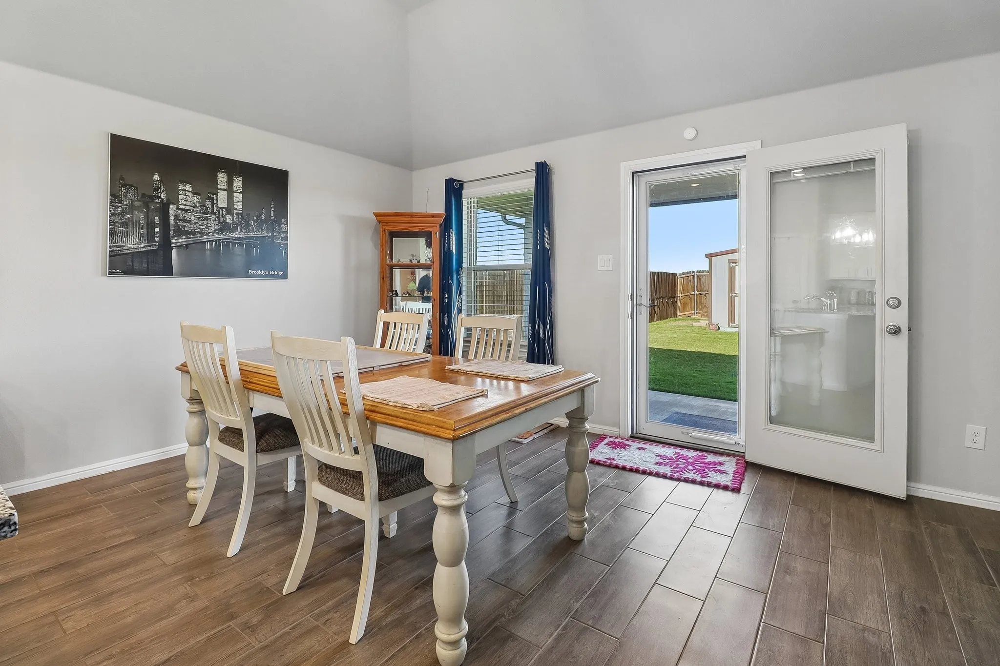 Dining area with vaulted ceilings, wood-finish flooring, and direct access to the backyard through a glass-paneled door
