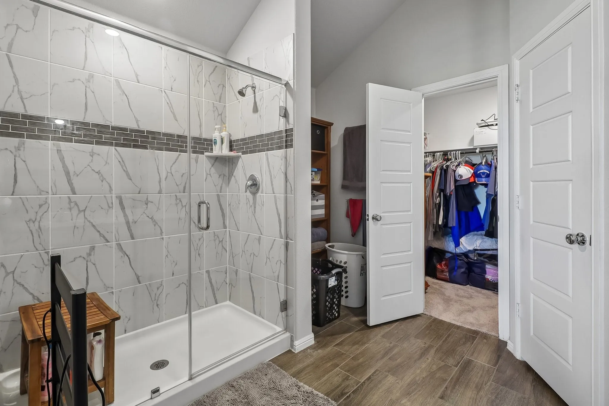 Glass-enclosed shower featuring large format tile with a mosaic accent band and built-in shelving