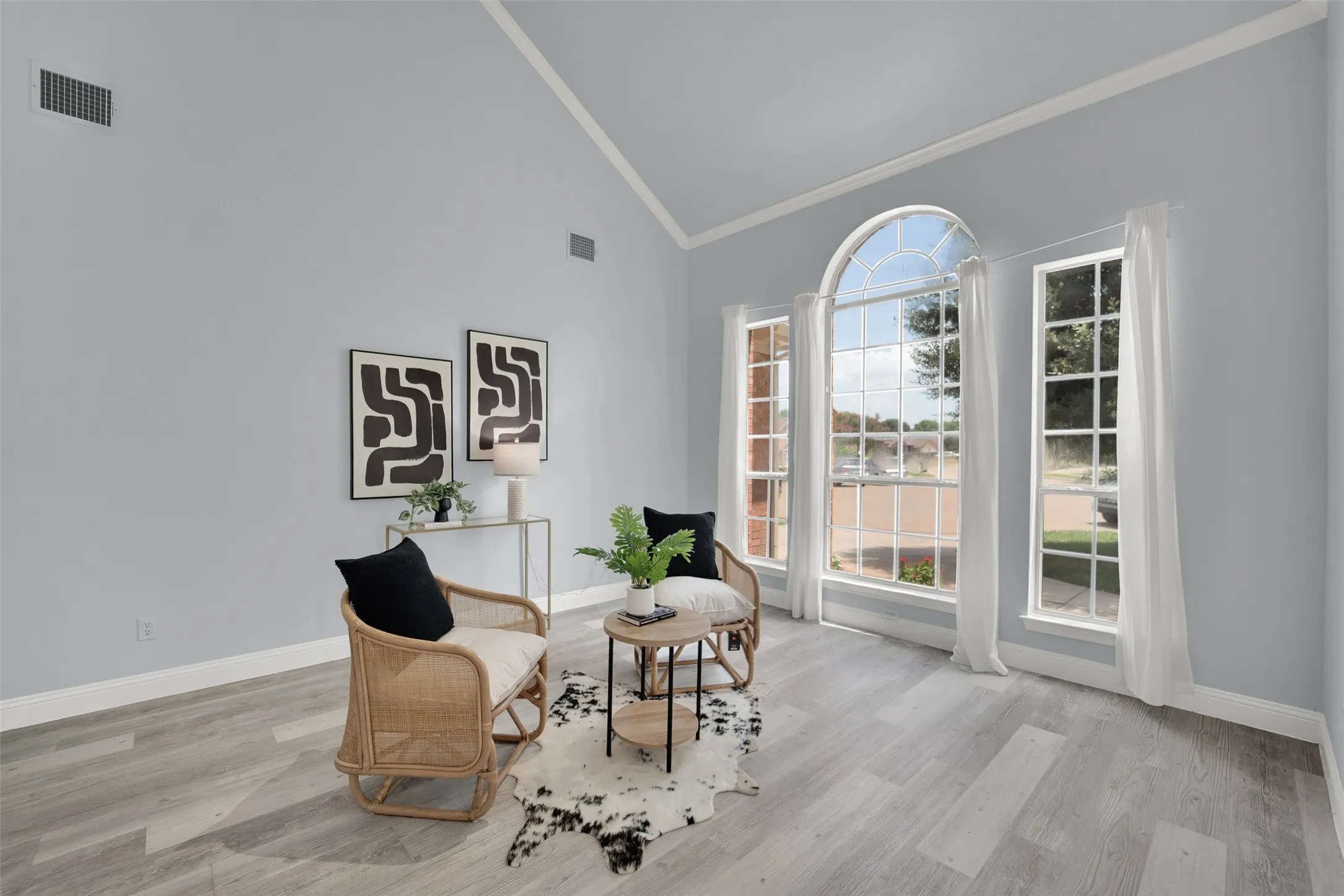 Vaulted ceiling room featuring light blue walls, wood-finish flooring, and white baseboards