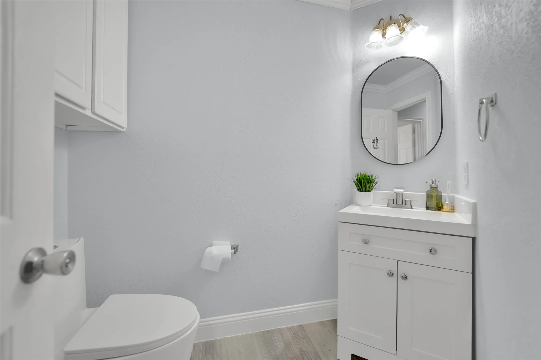 Bathroom featuring a single vanity with storage, a rectangular undermount sink, and a framed oval mirror