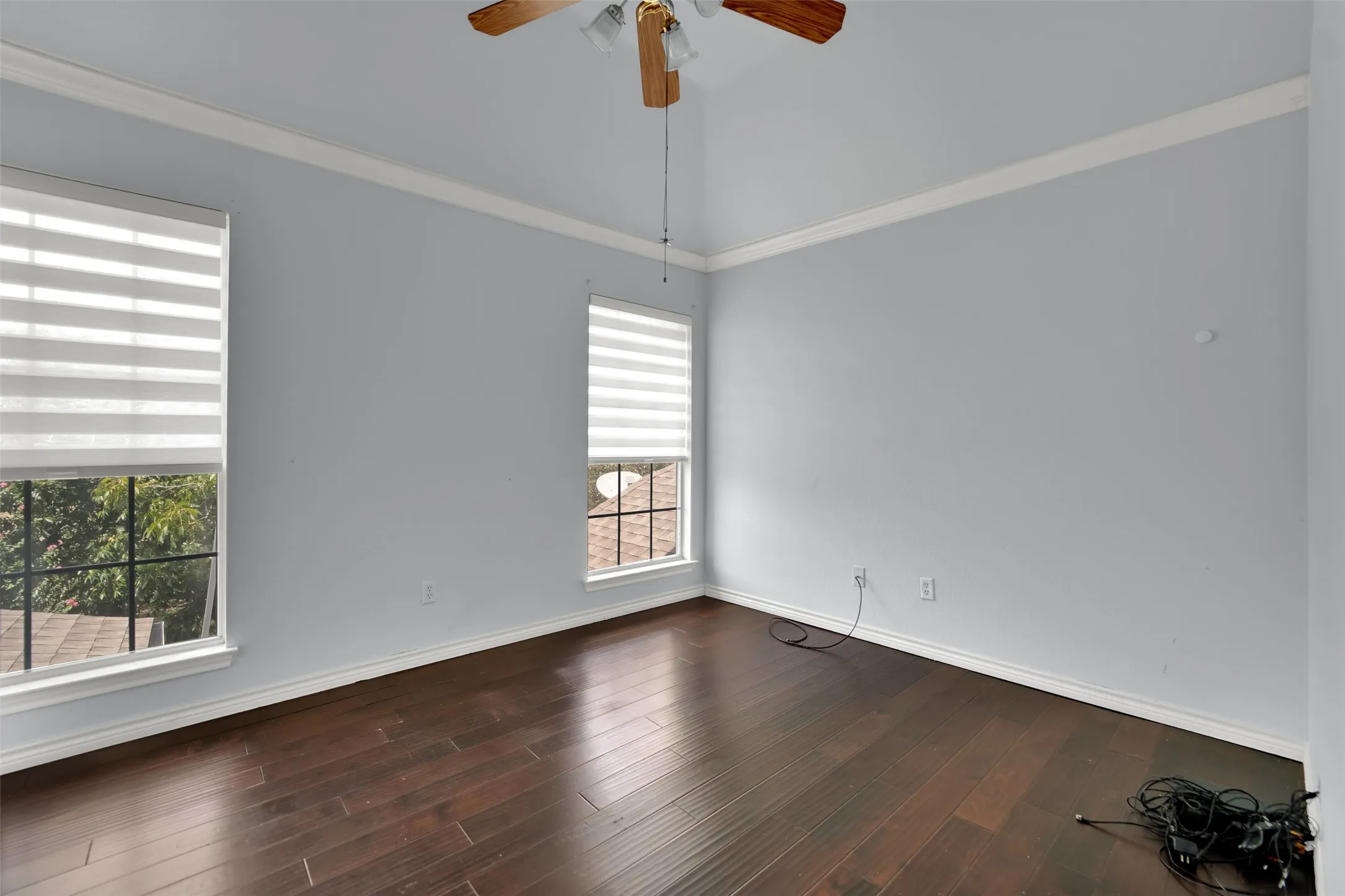 Room featuring dark wood-finish flooring, light blue walls, and white crown molding