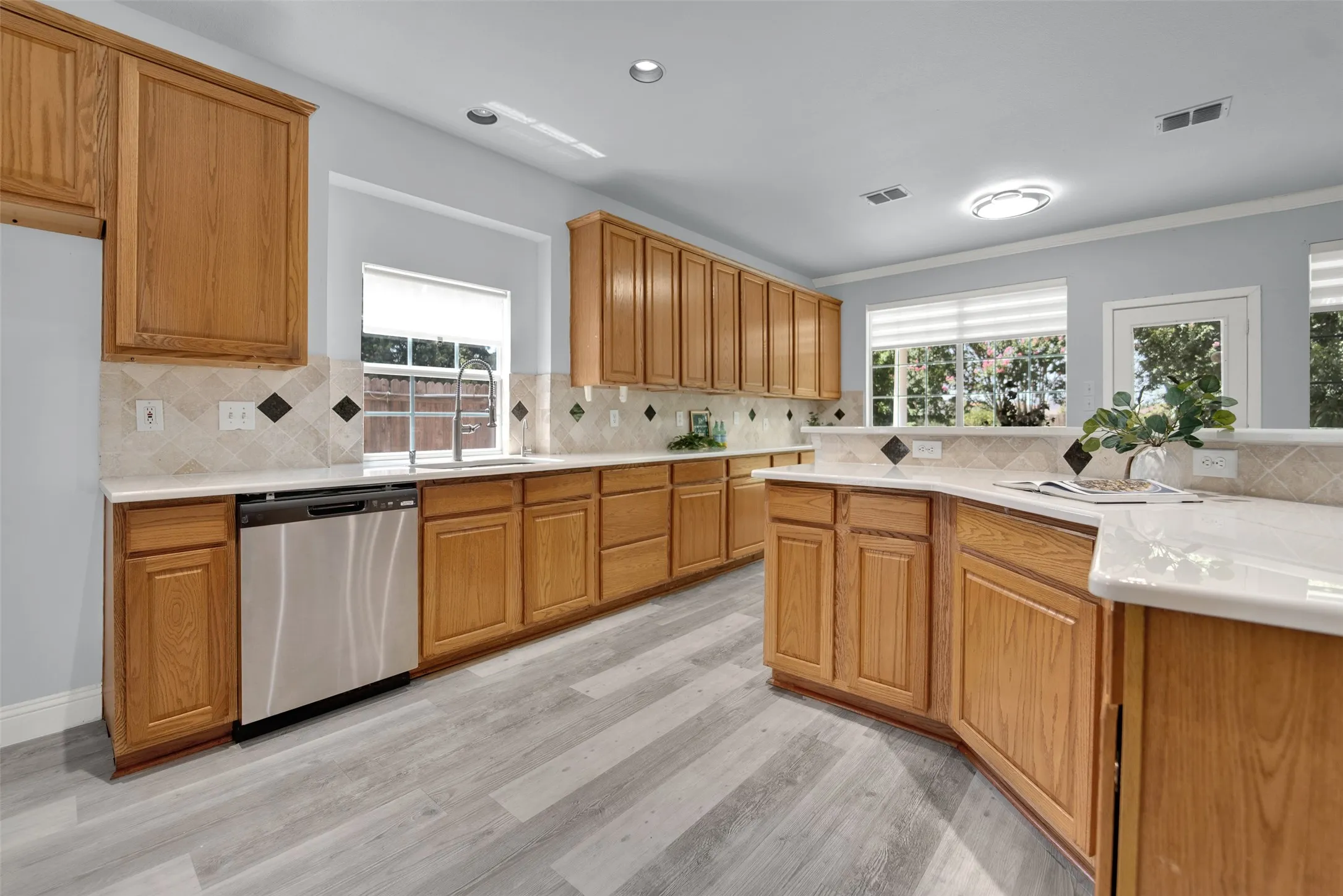 Spacious kitchen featuring light wood cabinetry, light-toned countertops, and a patterned tile backsplash