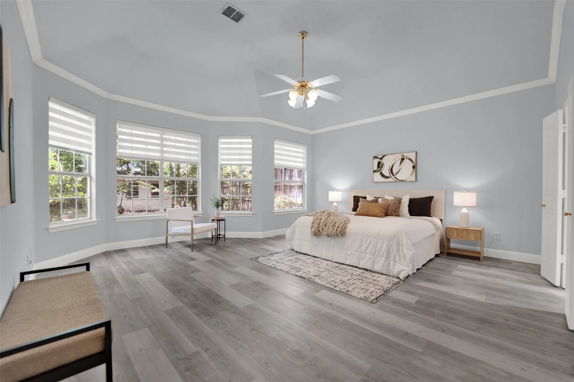 Spacious room featuring light wood-finish flooring, vaulted ceiling, and crown molding