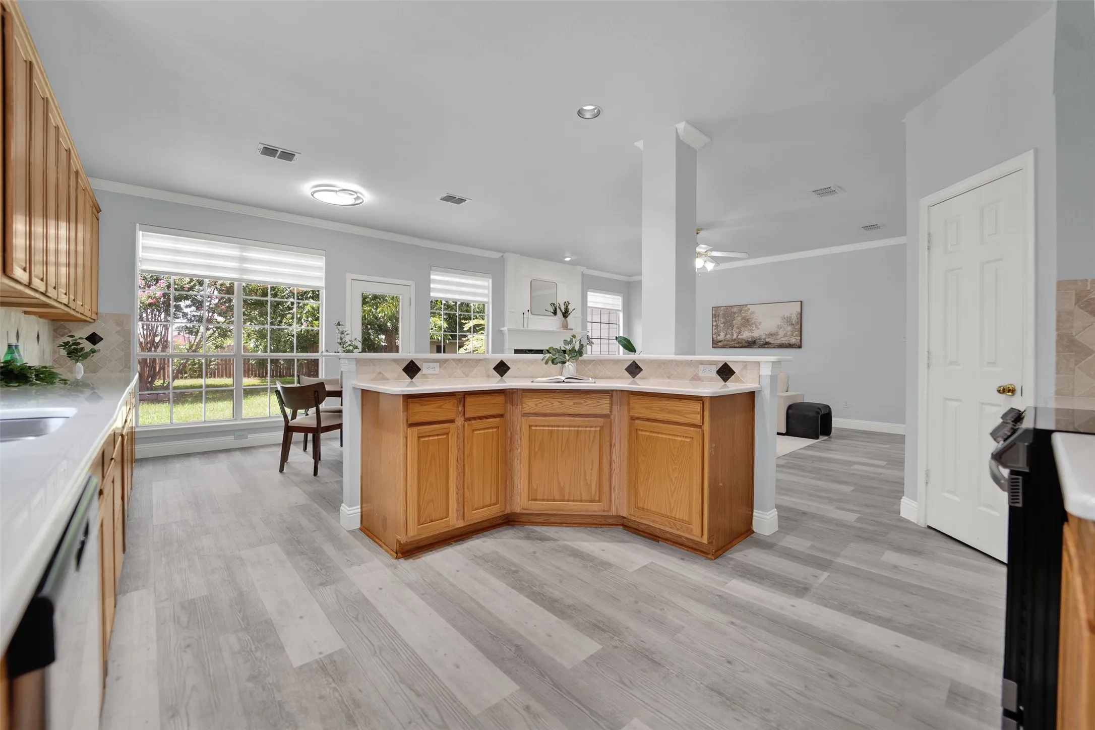 Kitchen featuring light wood cabinetry, light-toned countertops, and a tiled backsplash