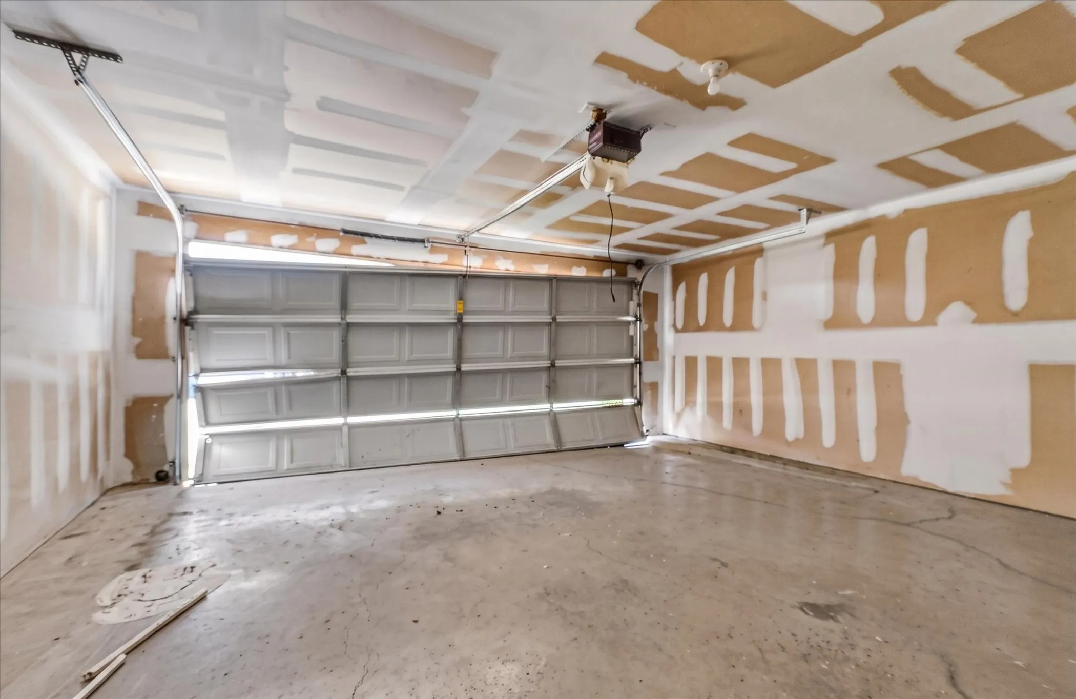 Spacious garage featuring a concrete floor, an overhead garage door, and visible ceiling joists