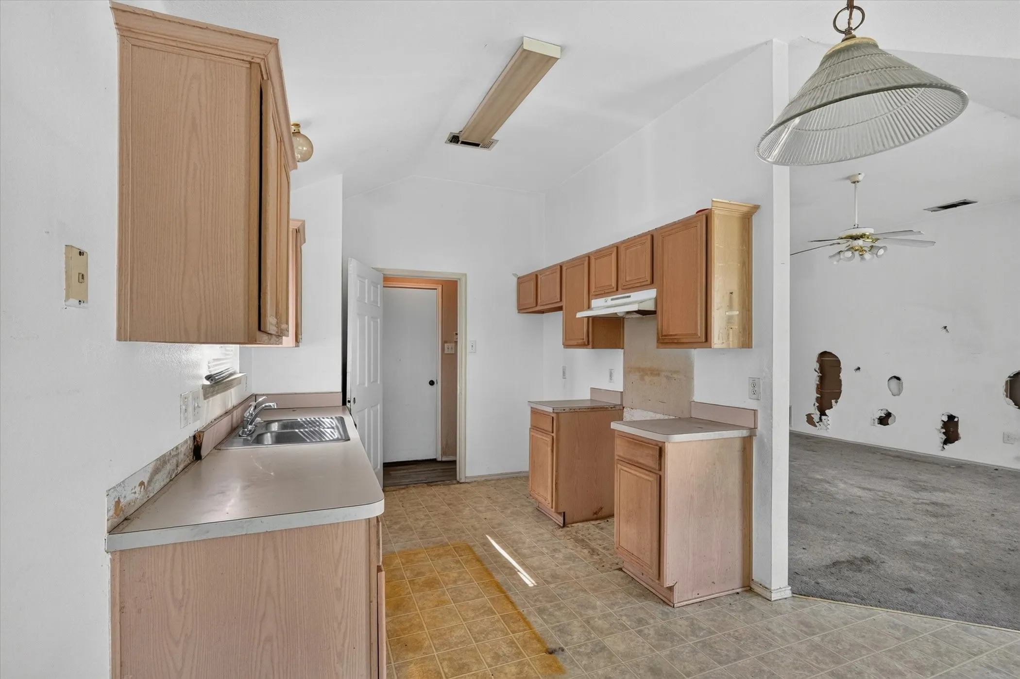 Kitchen featuring wood-finish cabinetry, laminate countertops, and a double basin stainless steel sink