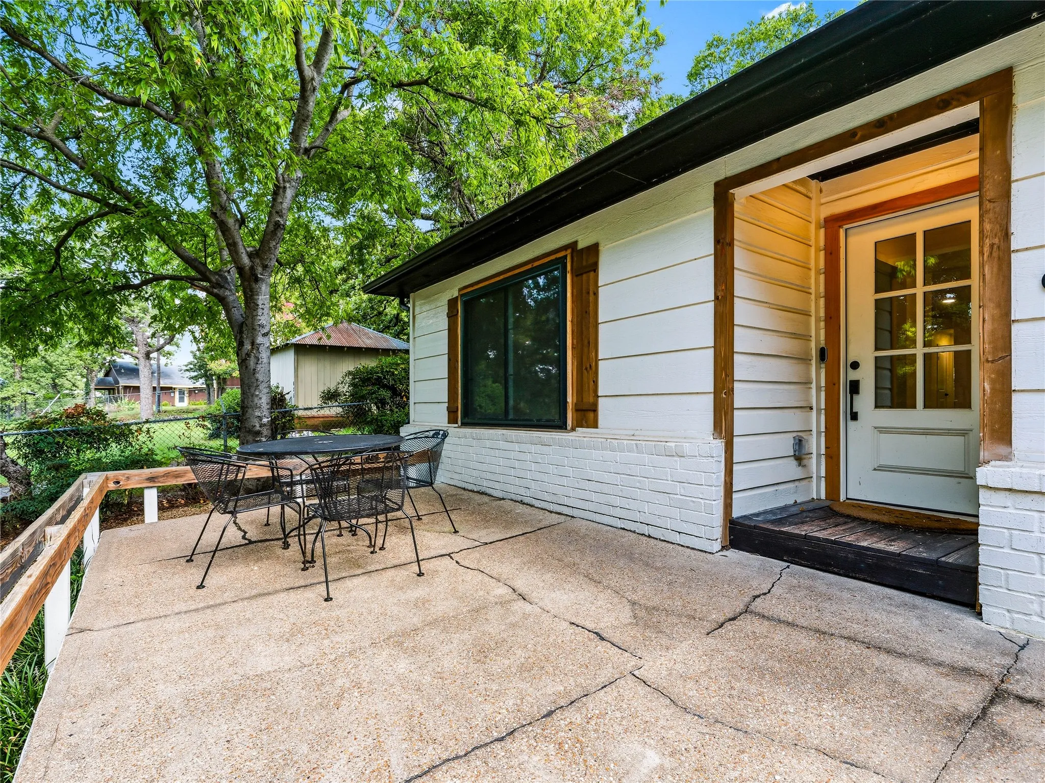 Expansive concrete patio with white exterior siding and brick accents
