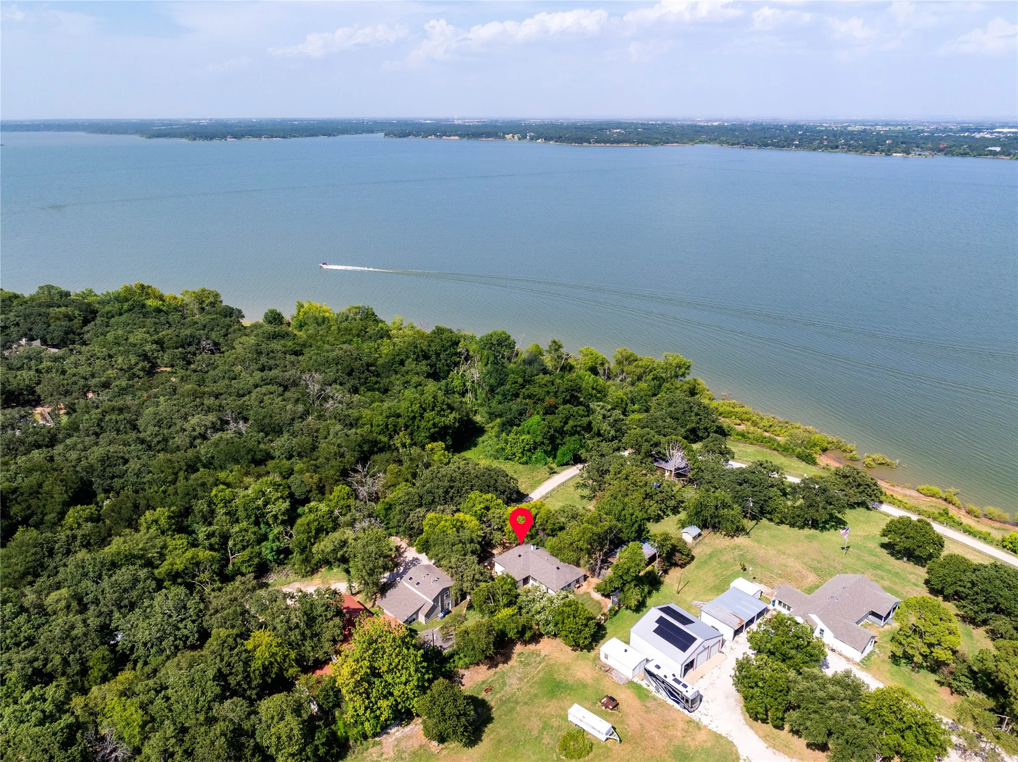 Expansive lakeside property featuring a primary residence with a gray roof and a prominent water frontage