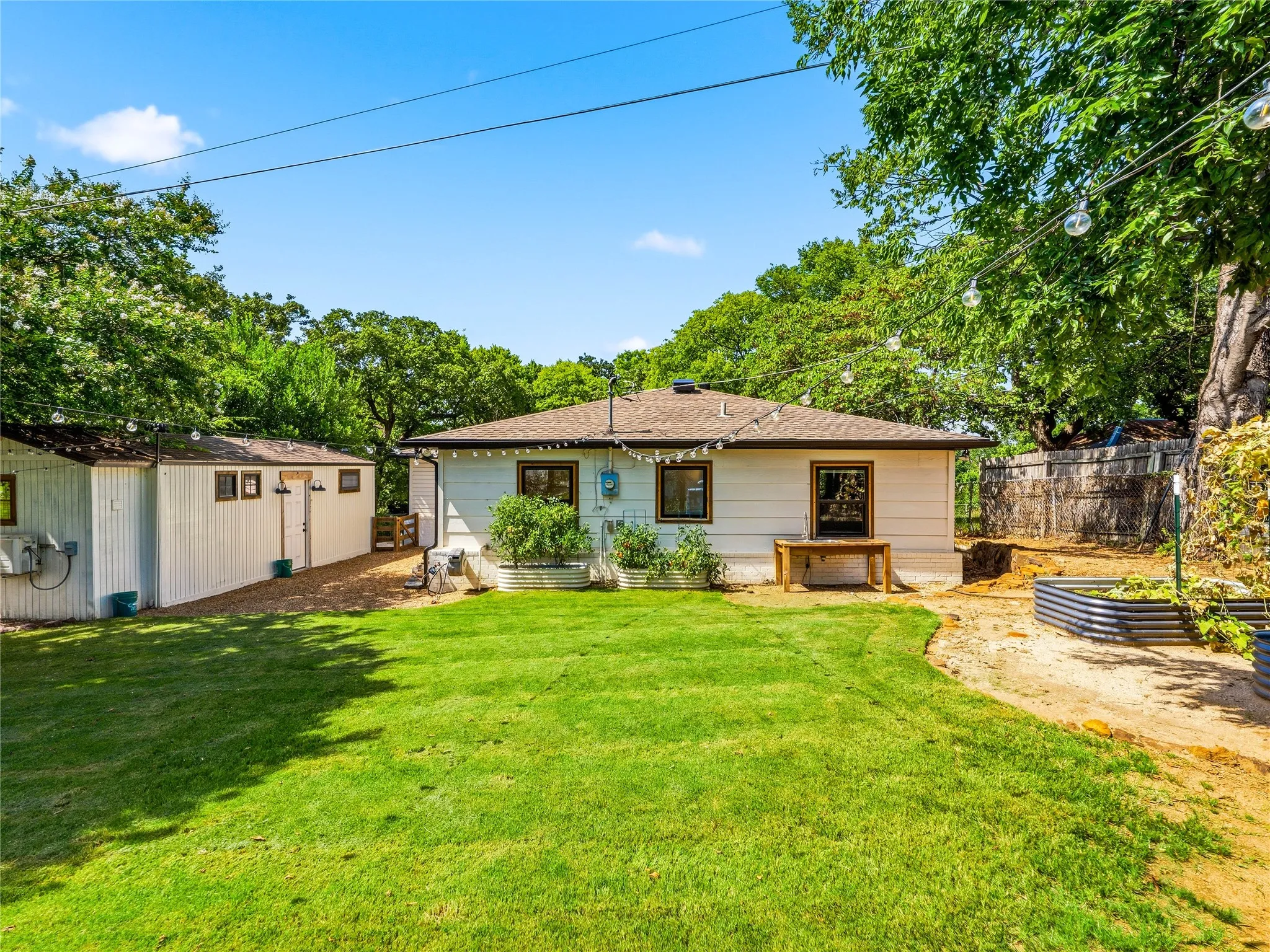 Spacious backyard featuring a manicured lawn, an auxiliary building with multiple exterior doors, and a detached shed