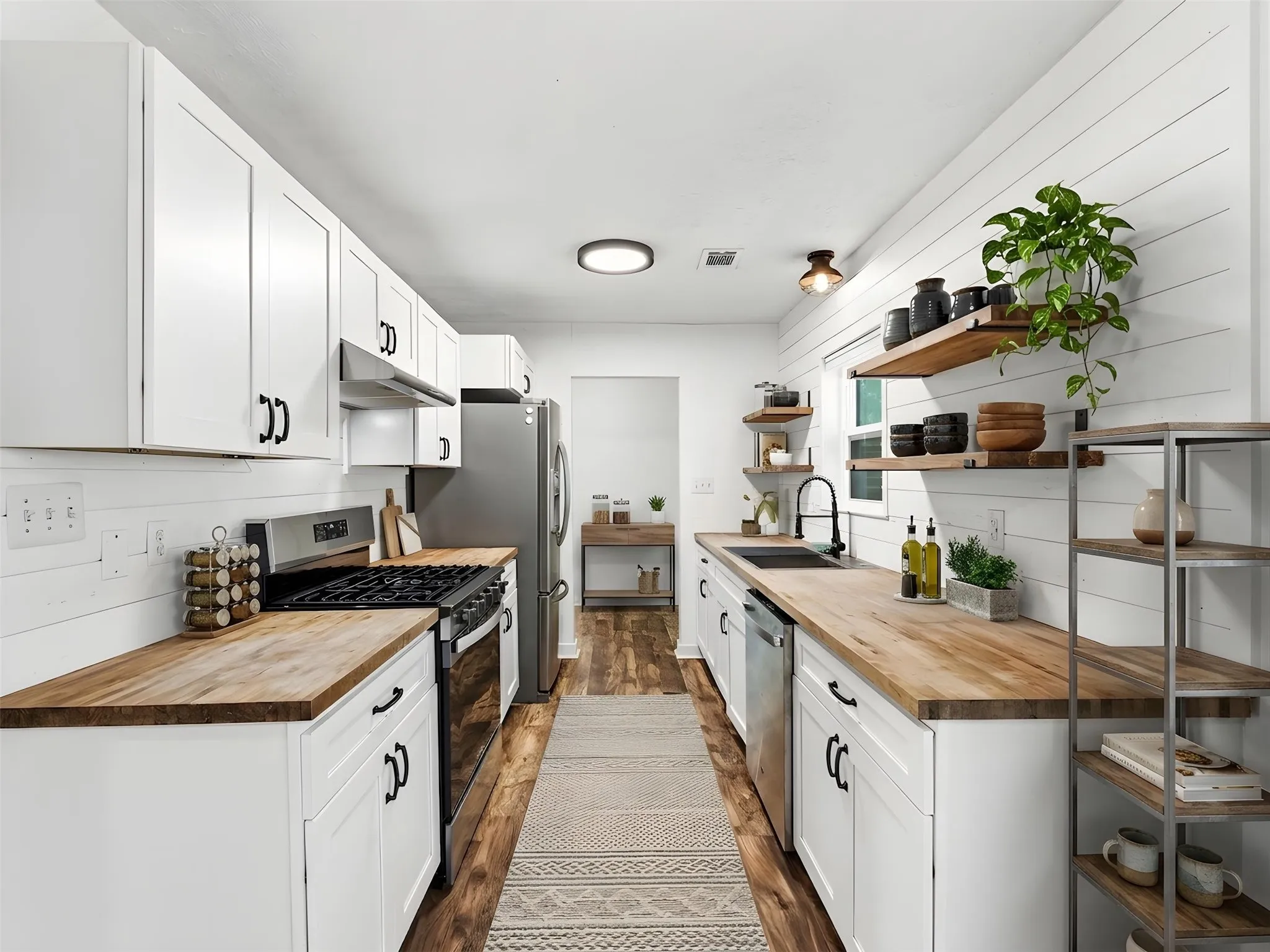 Modern kitchen featuring white shaker cabinetry, wood-finish countertops, stainless steel appliances, and shiplap accent walls