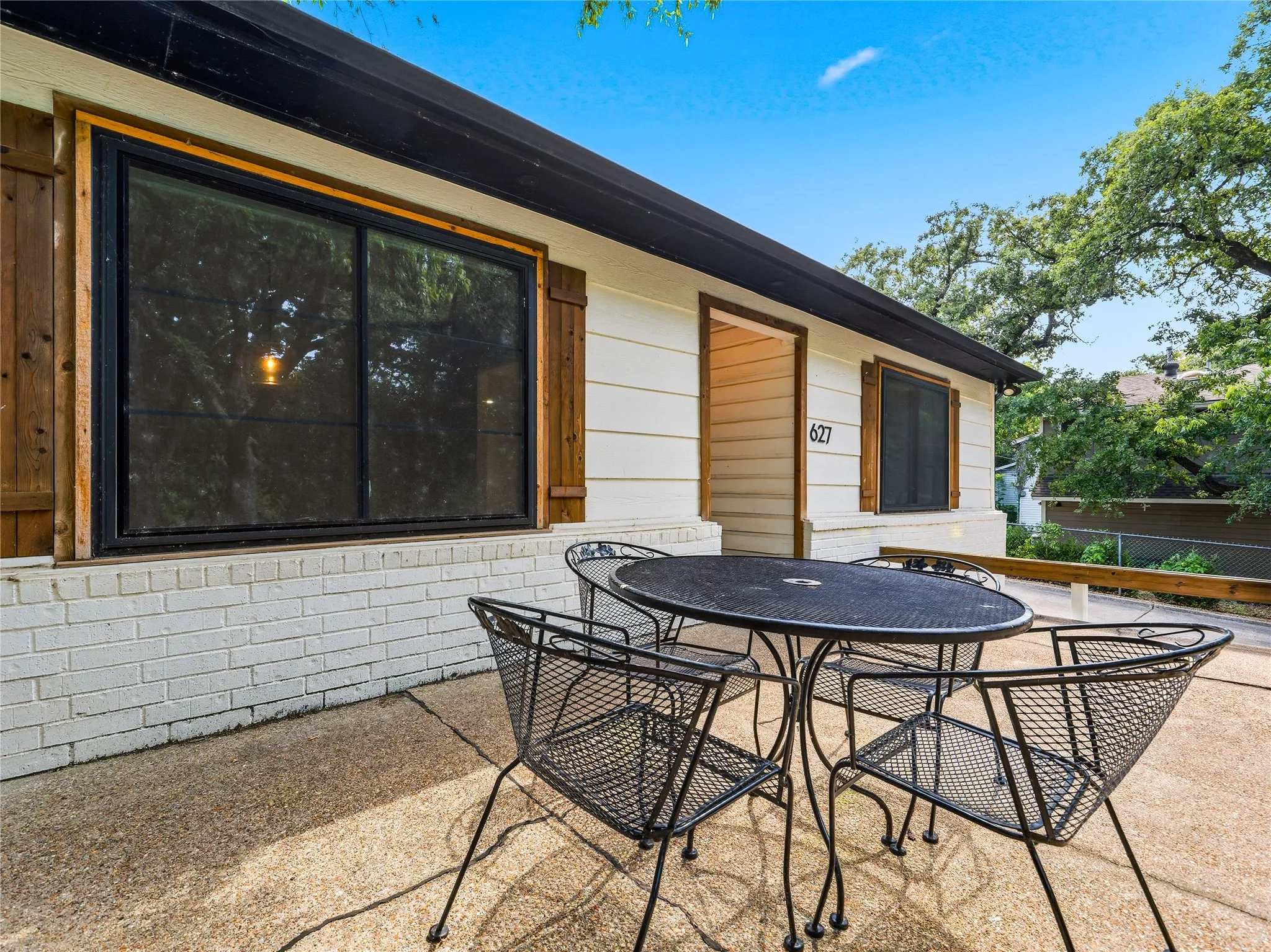 Exterior patio featuring a concrete surface, white painted brick, horizontal siding, and natural wood window shutters