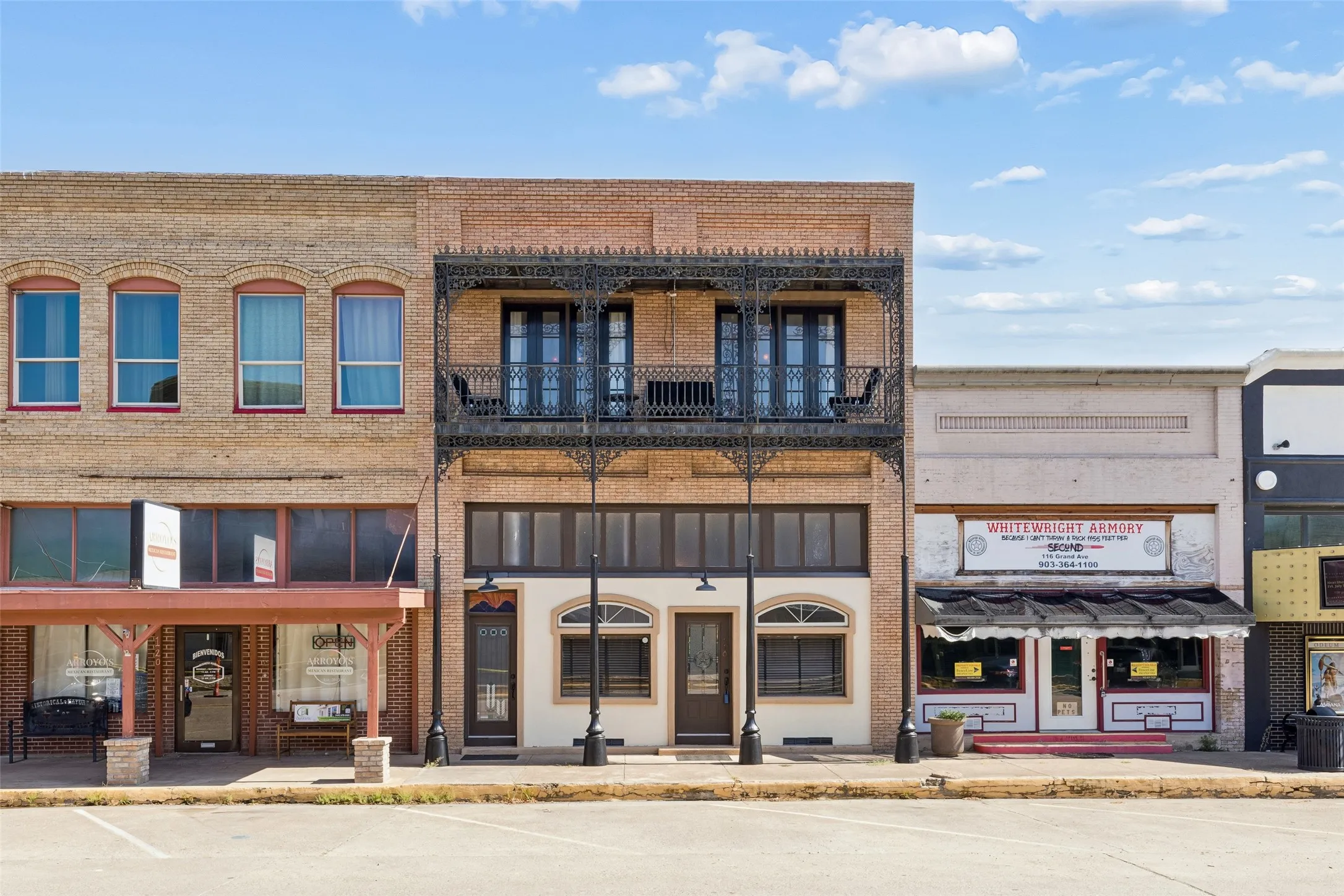 Brick facade featuring a wrought-iron balcony and multiple arched windows