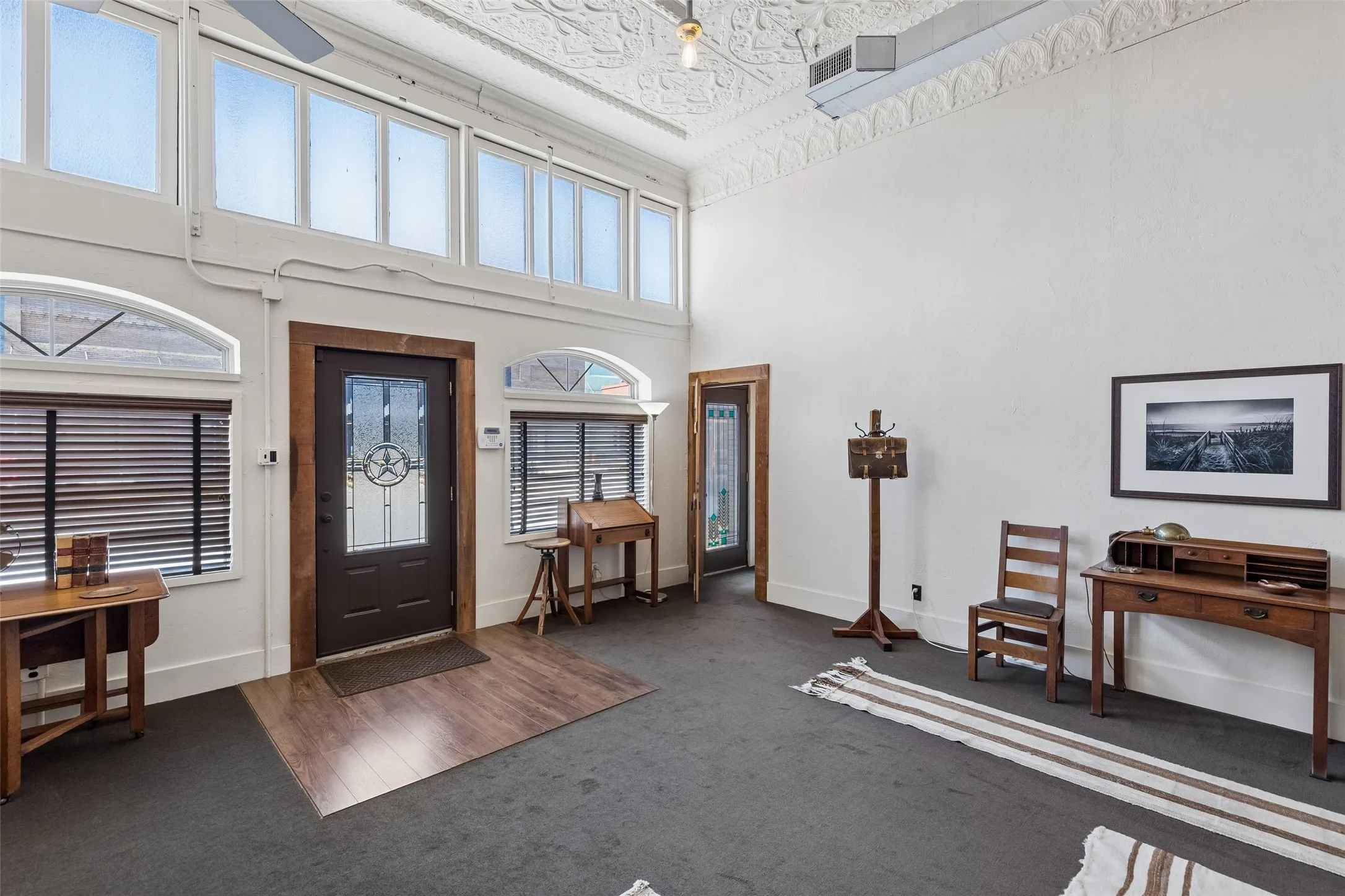 Entryway featuring a dark wood-finish door with decorative glass, flanked by arched windows with horizontal blinds