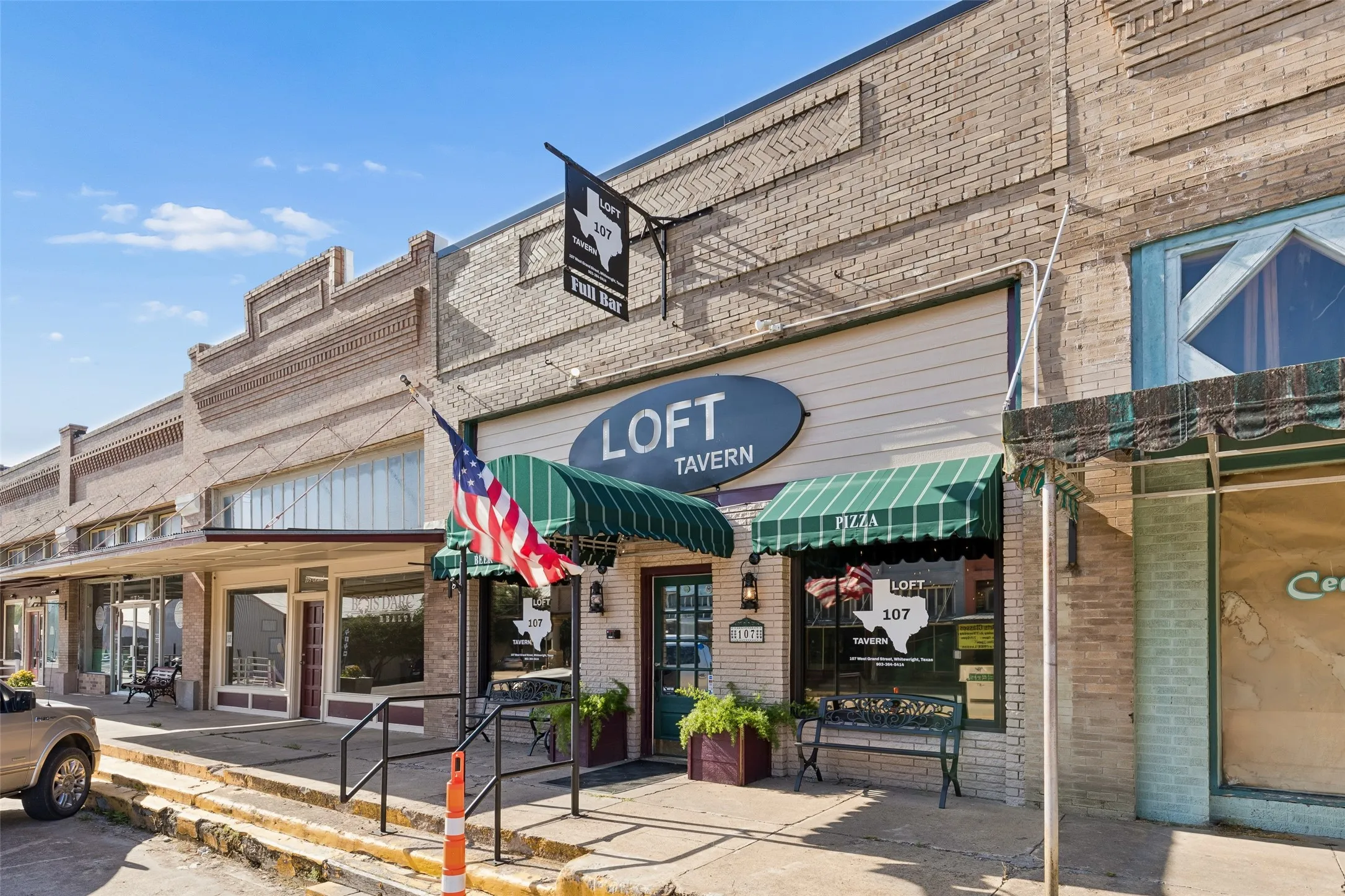 Commercial building with brick facade and green striped awnings