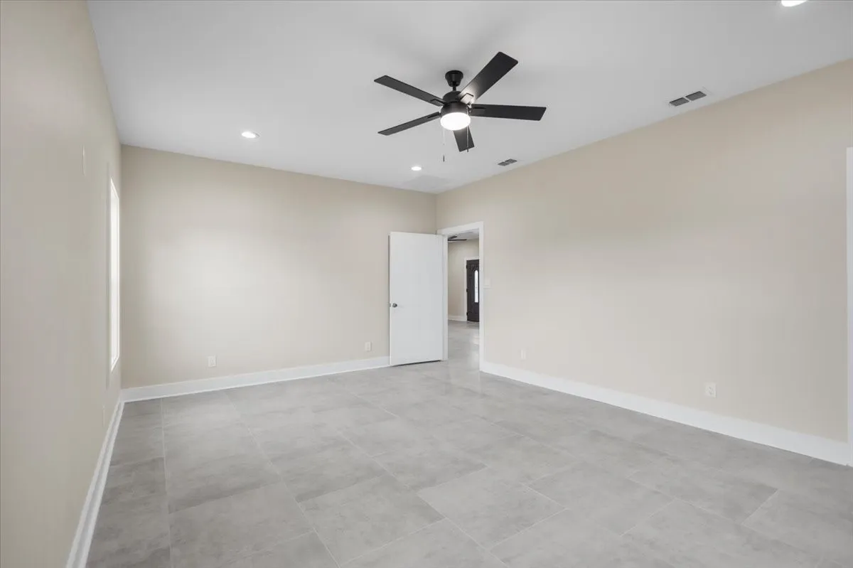 Spacious room featuring light gray tile flooring, a vaulted ceiling, and recessed lighting