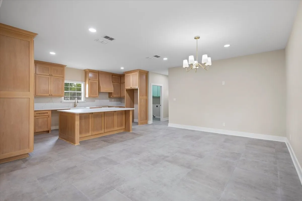 Open-concept kitchen and dining area featuring light wood cabinetry, a central island with countertop, and light-toned tile flooring