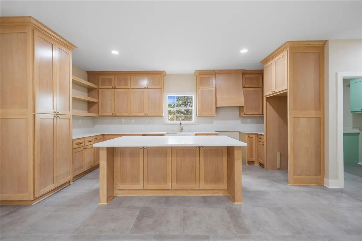 Kitchen featuring a central island, light wood-finish cabinetry, white countertops, built-in shelving, and recessed lighting