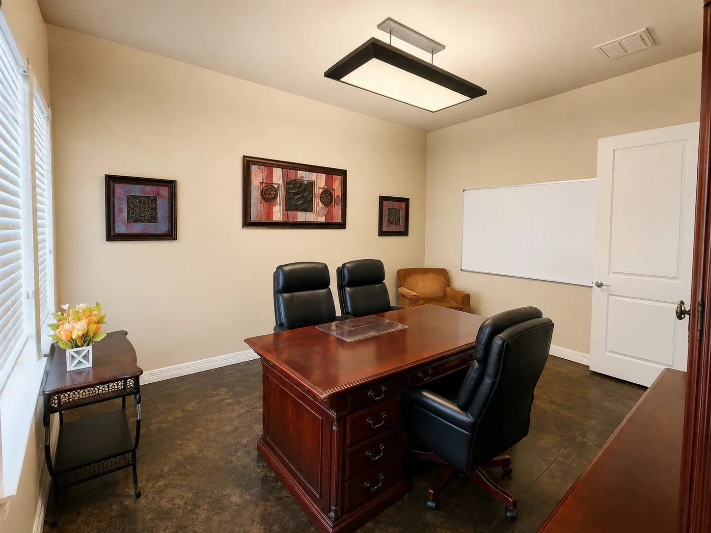Dedicated office space featuring textured flooring, a window with horizontal blinds, and a white interior door