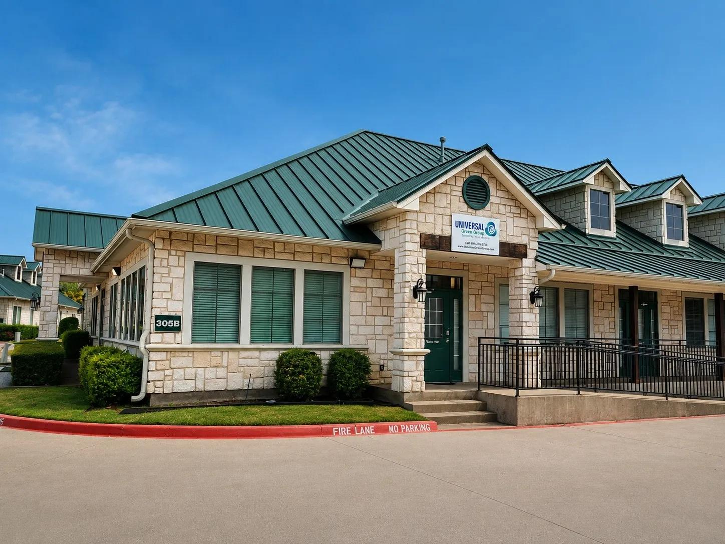 Stone-clad building featuring a dark green metal roof, multiple dormer windows, and a prominent entry porch